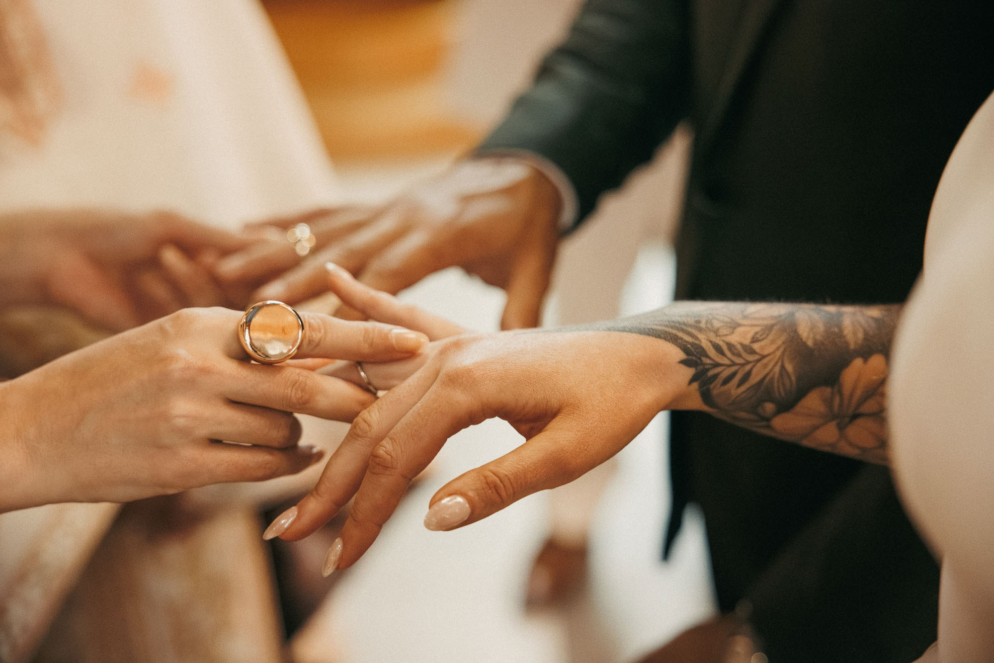 A wedding ring is placed on the bride’s tattooed hand.