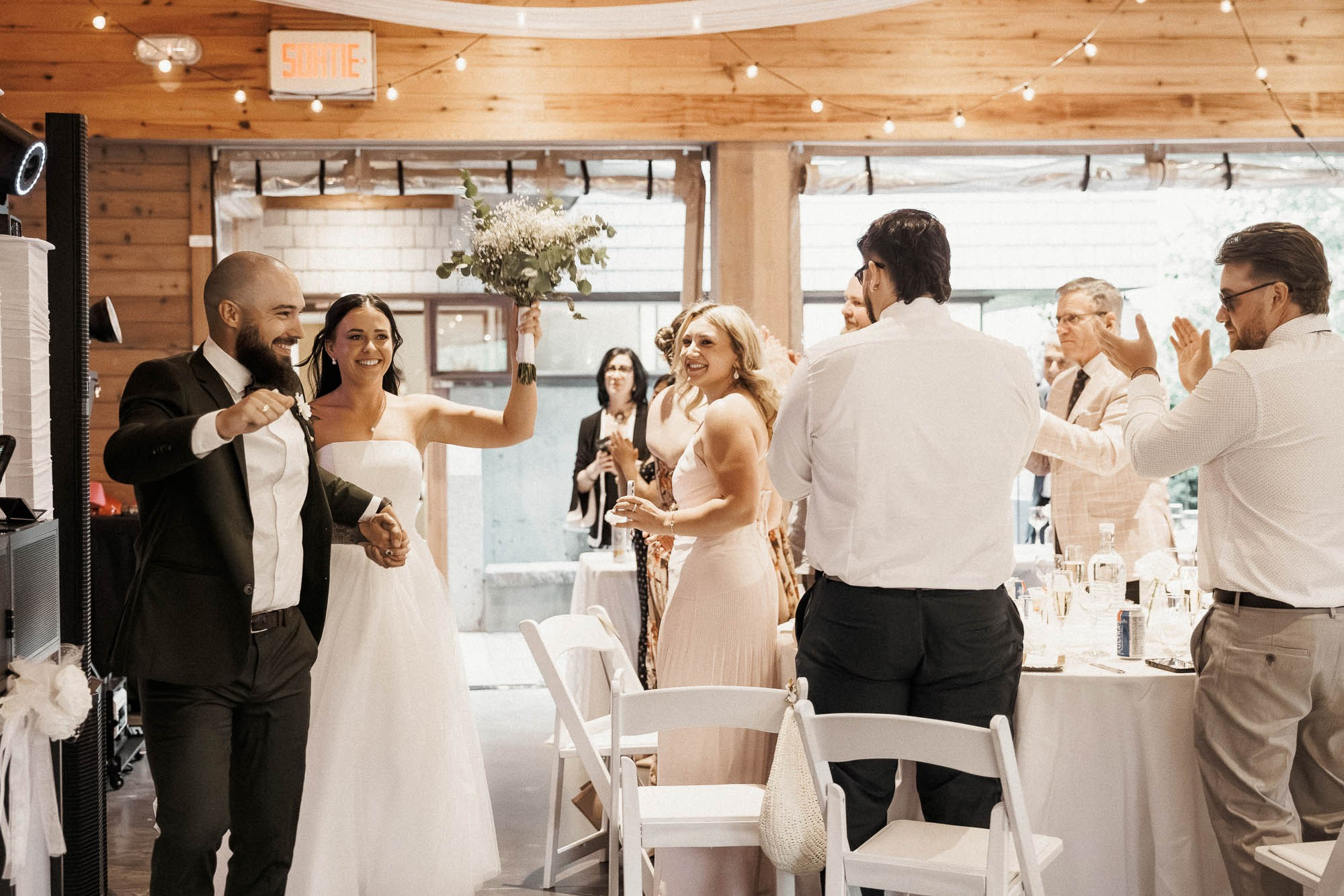 Kendyl and Mikey smile and raise their hands as guests welcome them.
