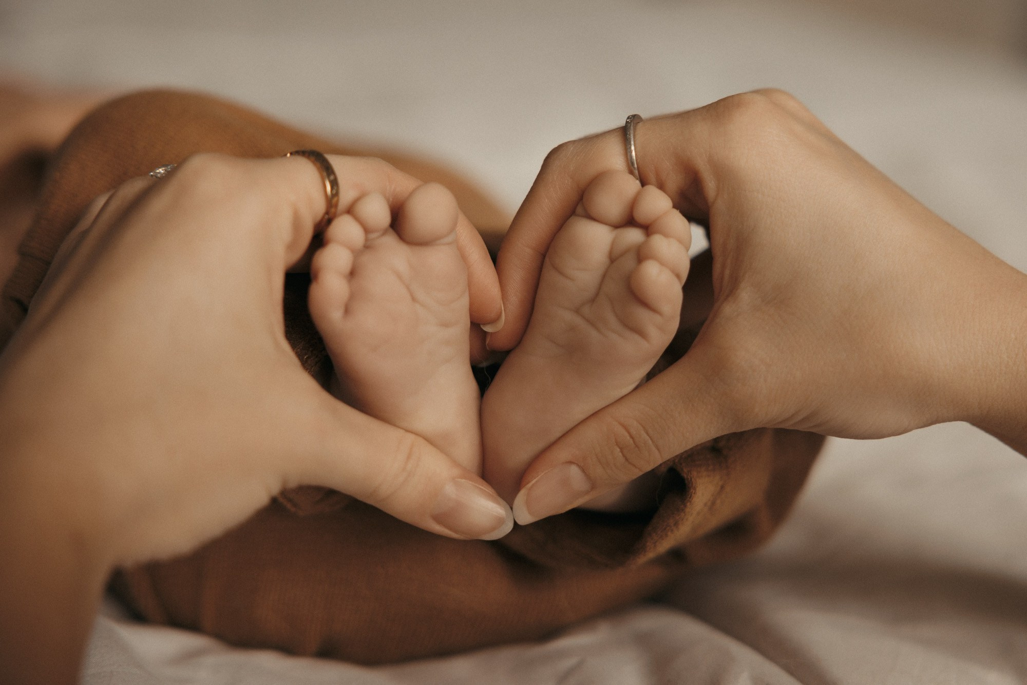 Parents entourant délicatement la tête de leur nouveau-né avec leurs mains
