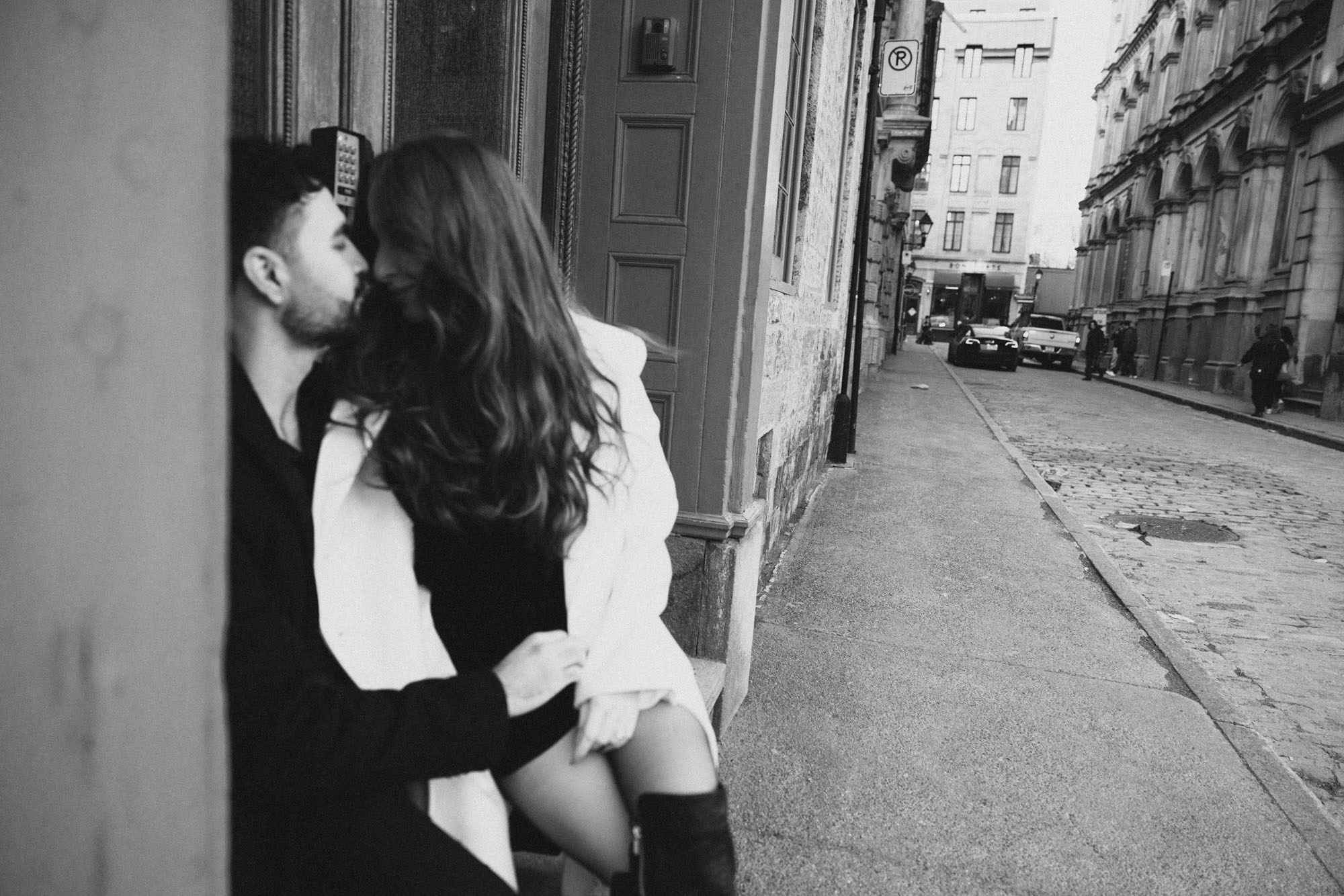 Black-and-white photograph of a couple kissing on a quiet Montreal street