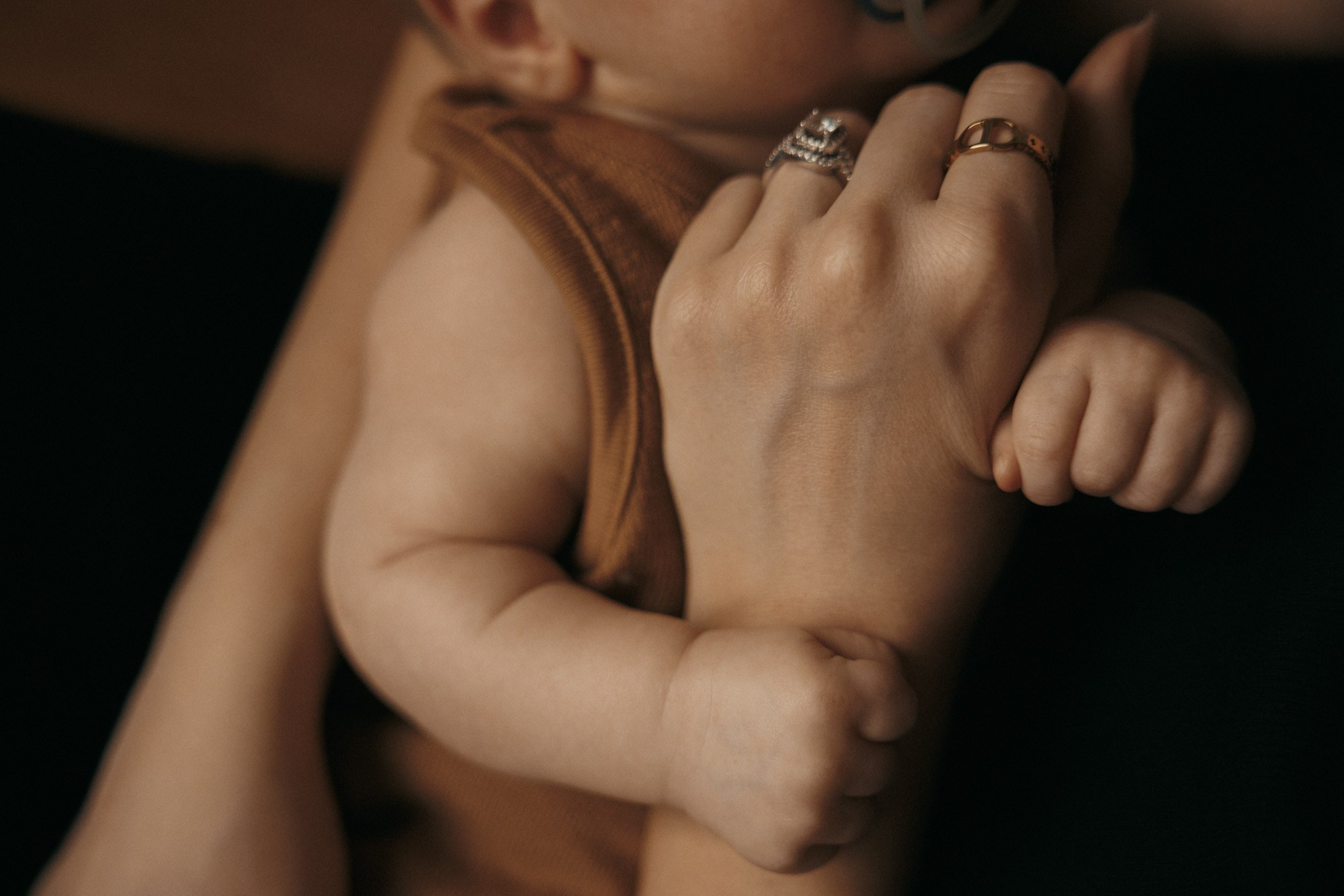 Nouveau-né blotti contre son parent pendant une séance photo lifestyle