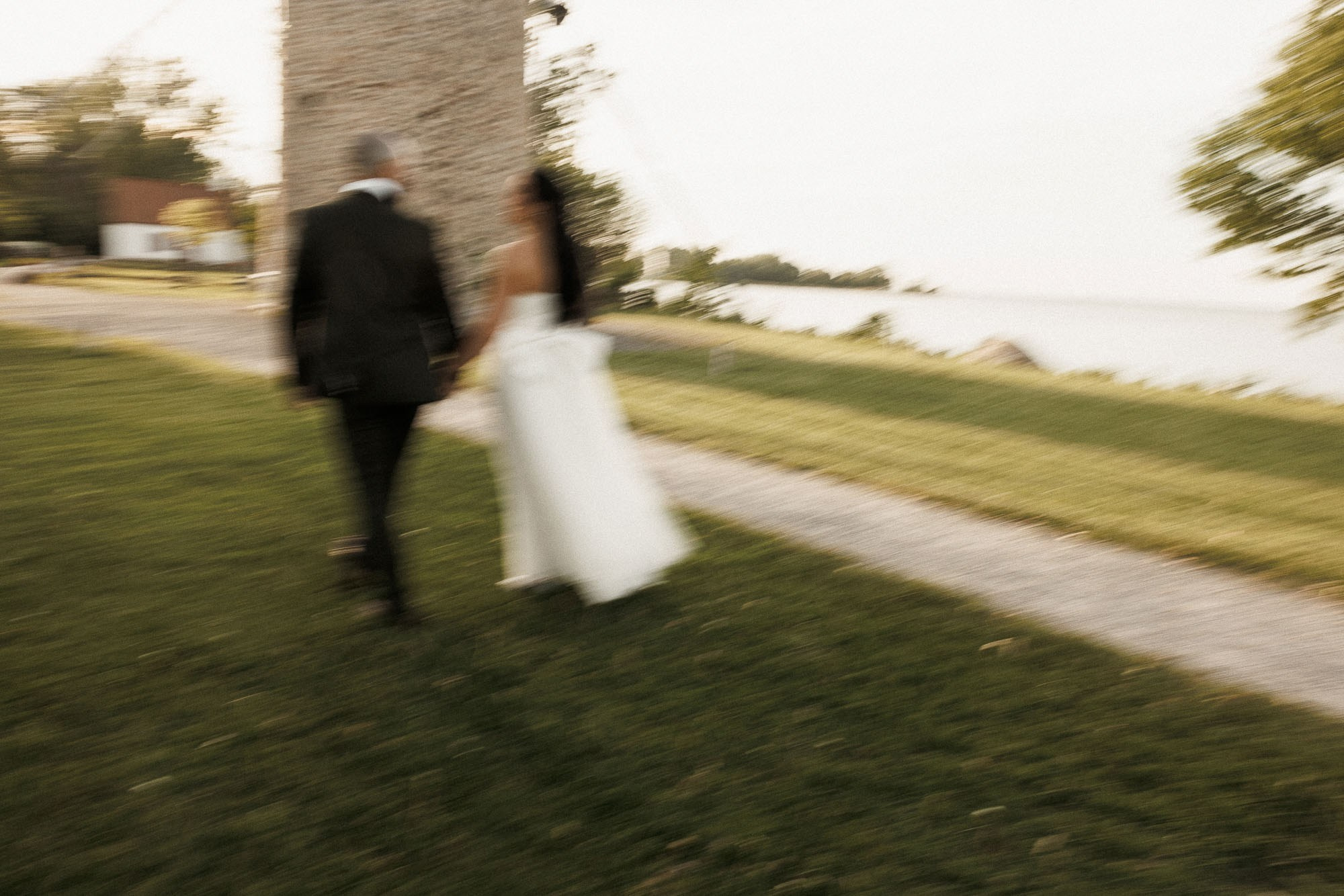 Intentional motion blur captures the newlyweds walking beside the waterfront.