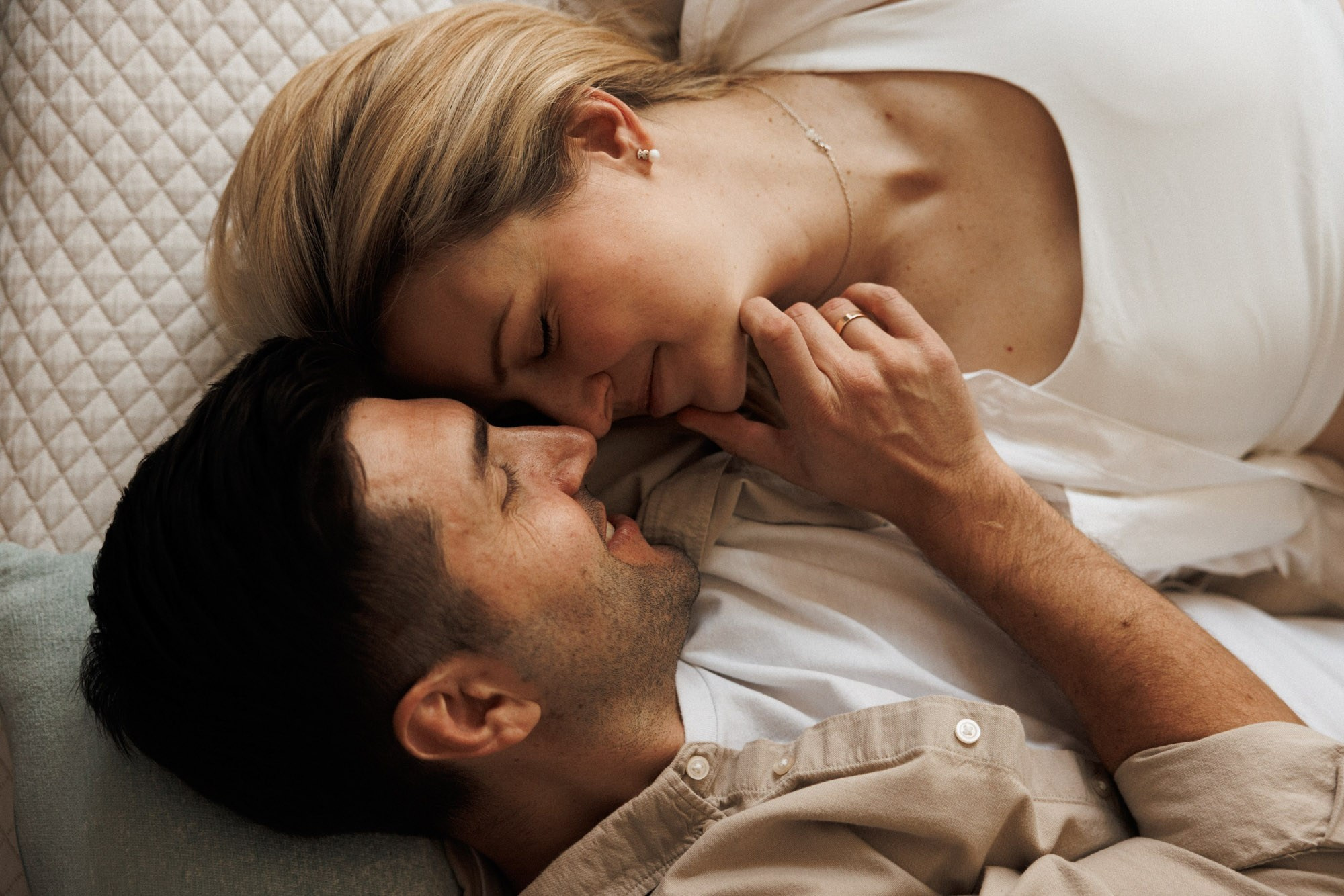 Expecting couple lying face-to-face during a relaxed at-home session
