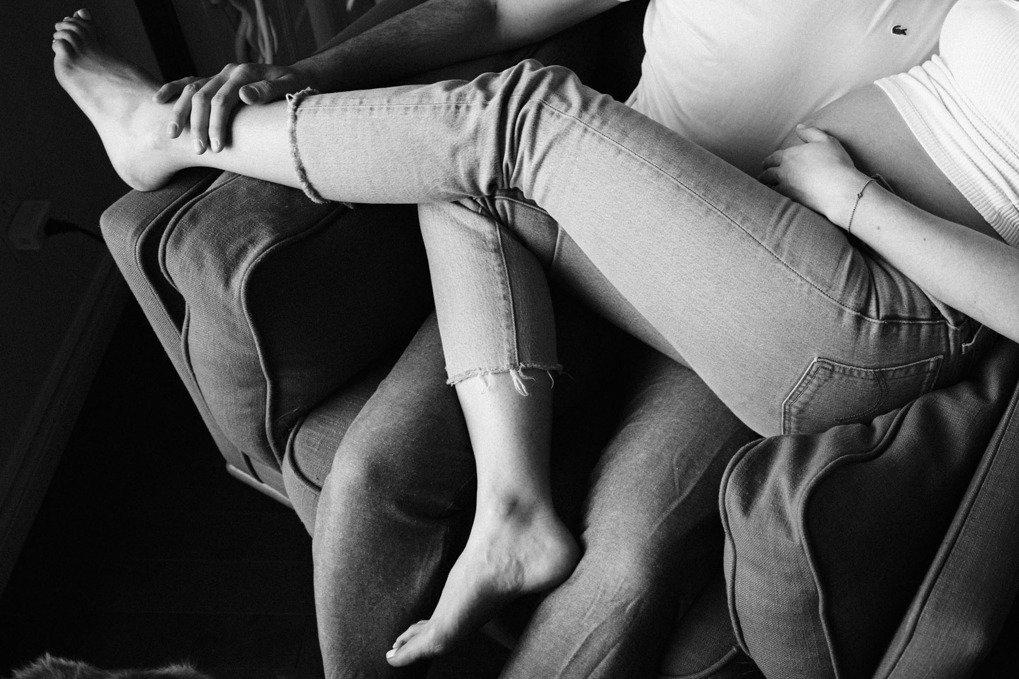 Black-and-white close-up of an expecting couple sitting close together
