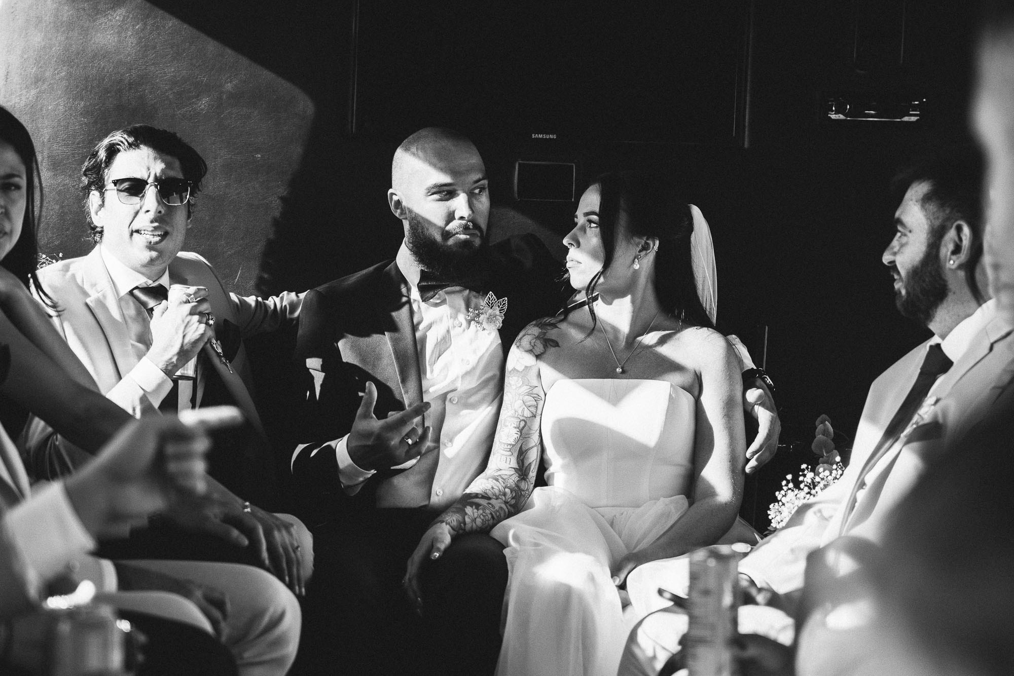 Kendyl and Mikey sit with friends in a party bus in a black-and-white candid.