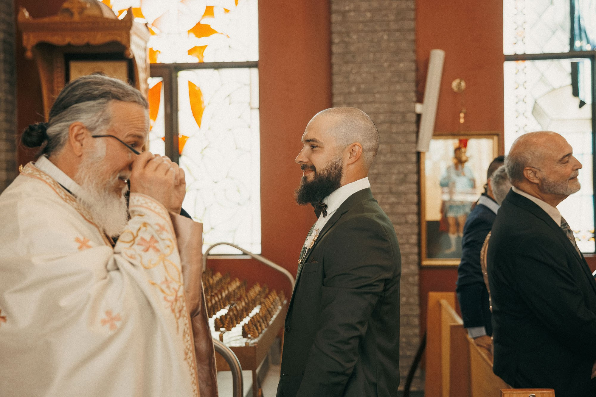 The groom smiles at an emotional priest during the wedding ceremony.