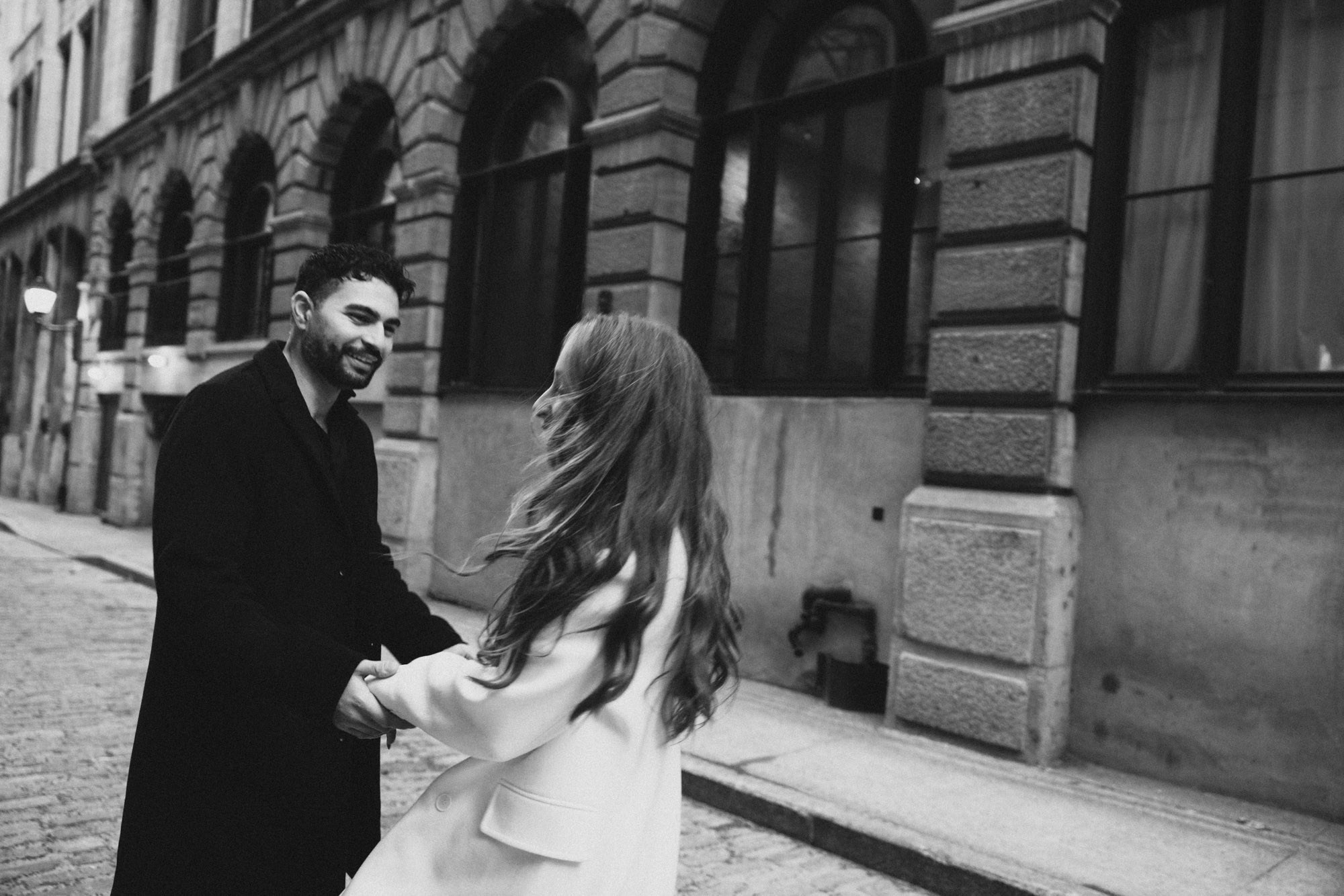 Black-and-white photograph of a couple laughing together on a cobblestone street in Old Montreal