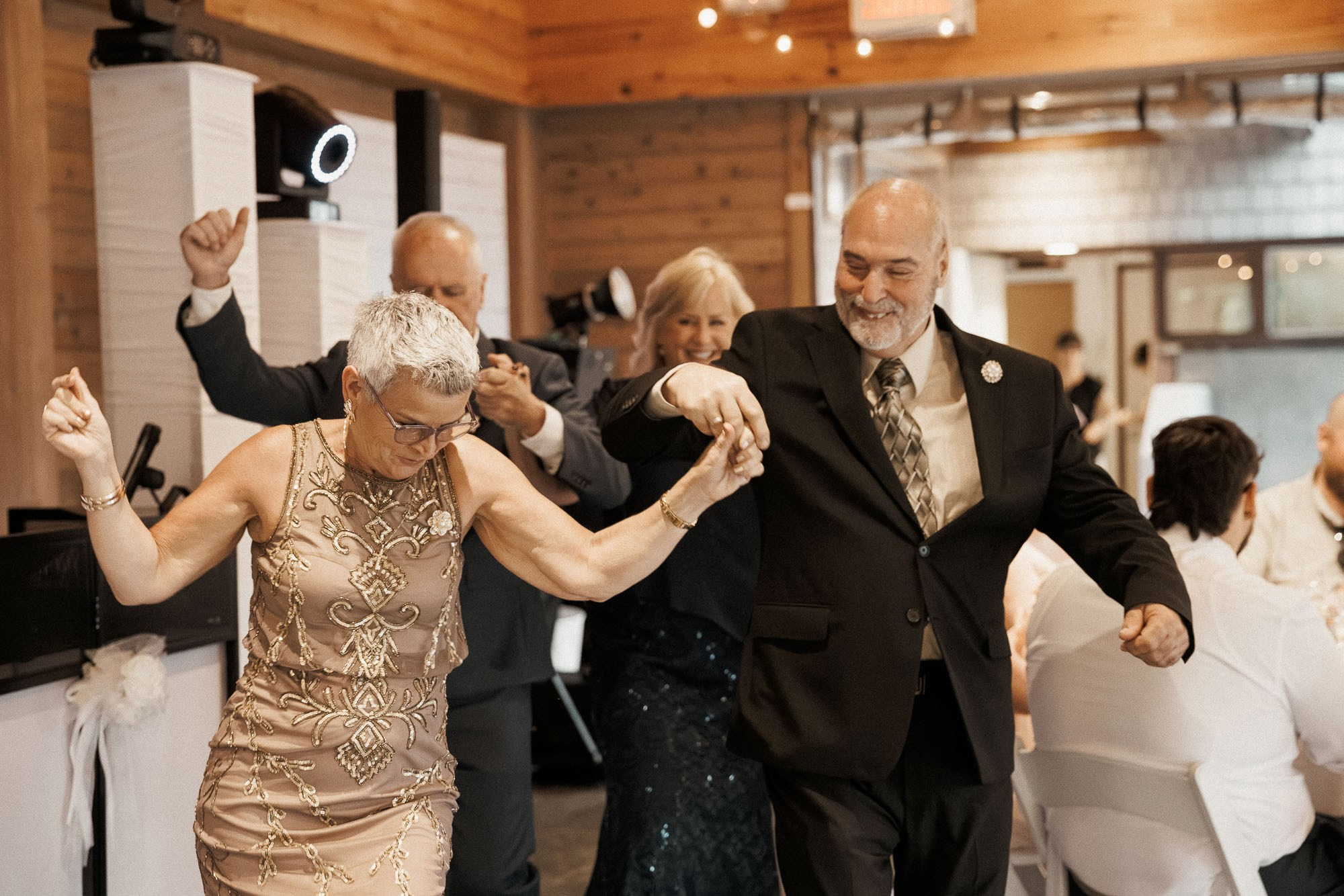 Older wedding guests dance hand in hand during the reception.