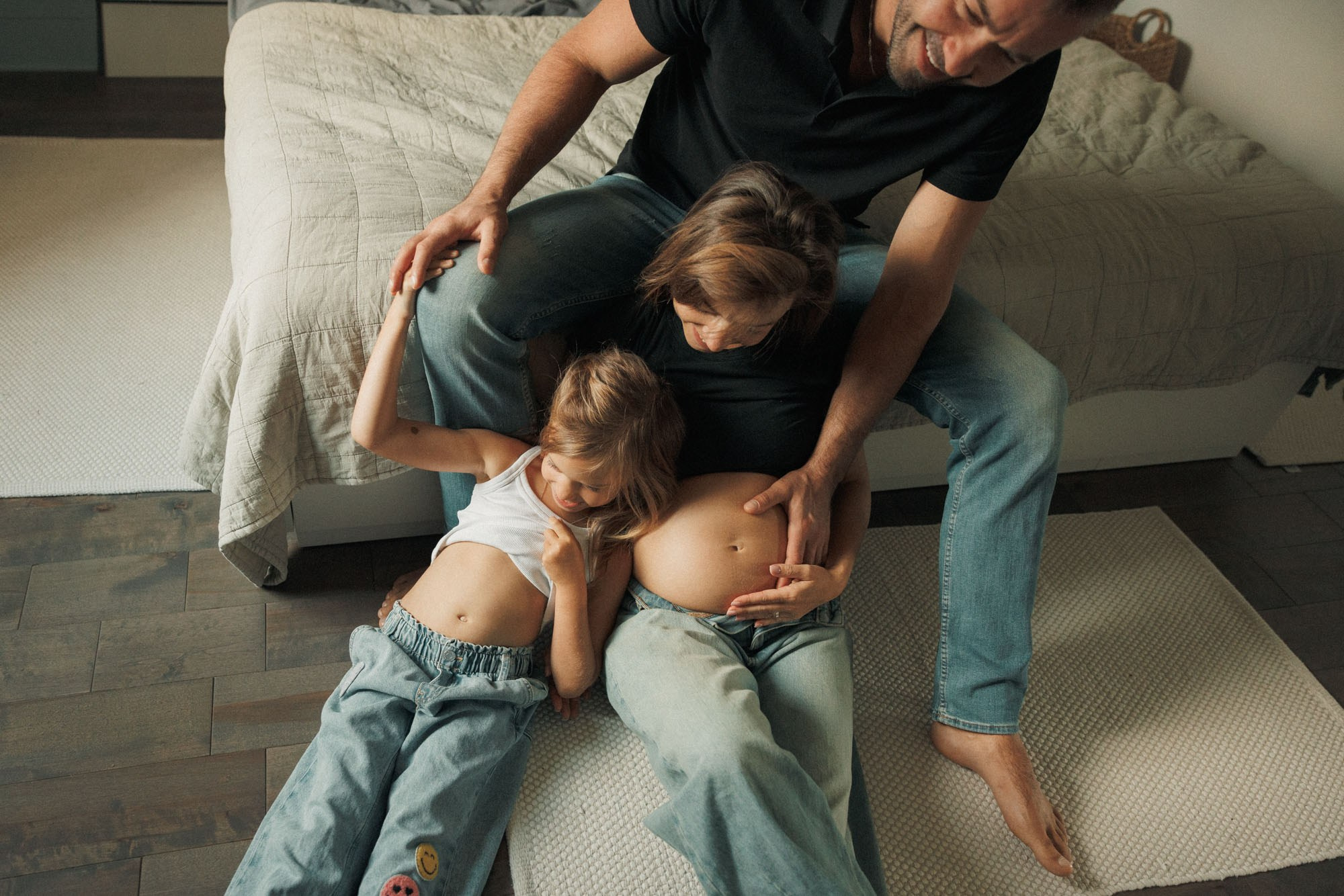 Older child listening to the baby while both parents sit together at home