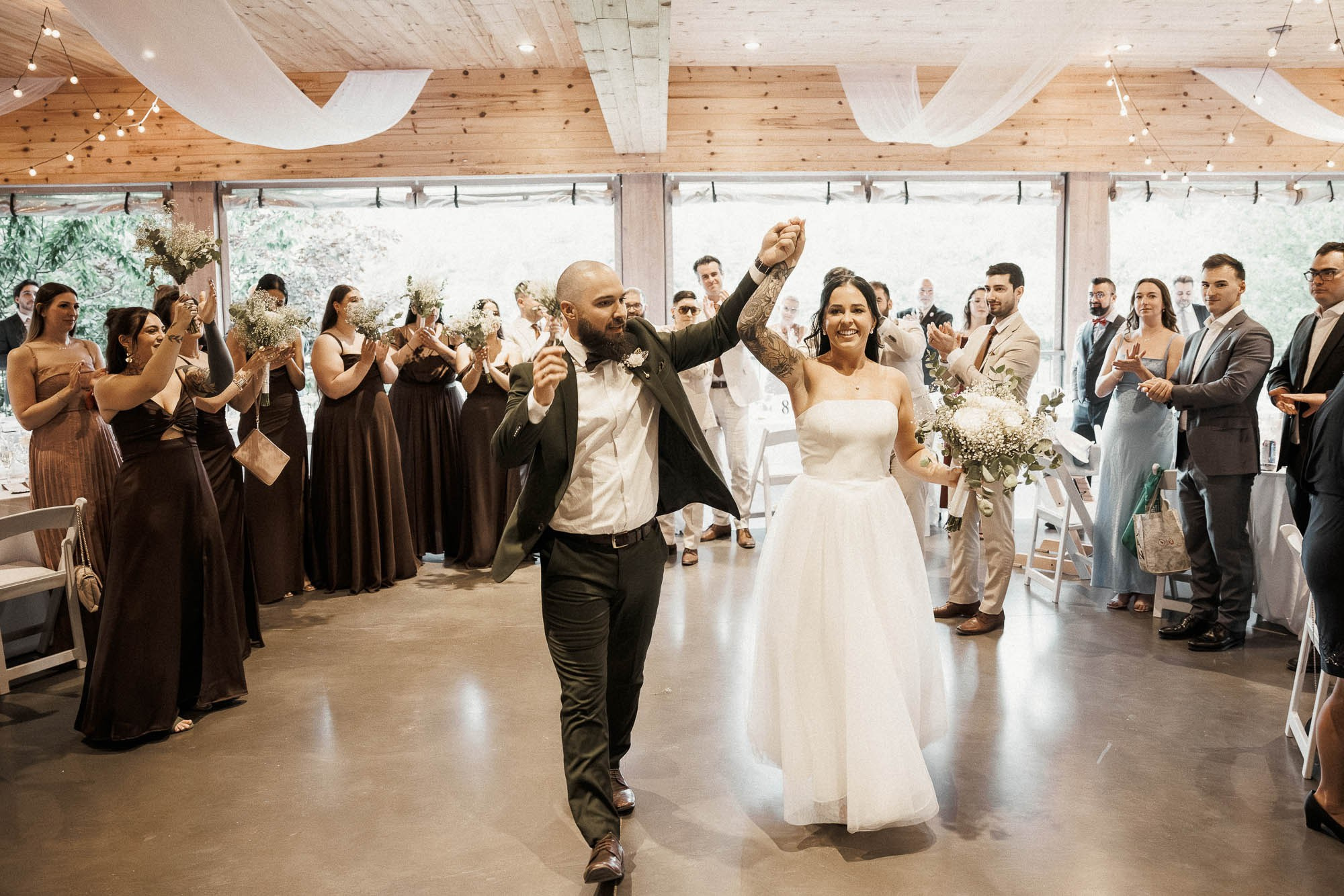 The newlyweds enter the reception hand in hand between applauding guests.