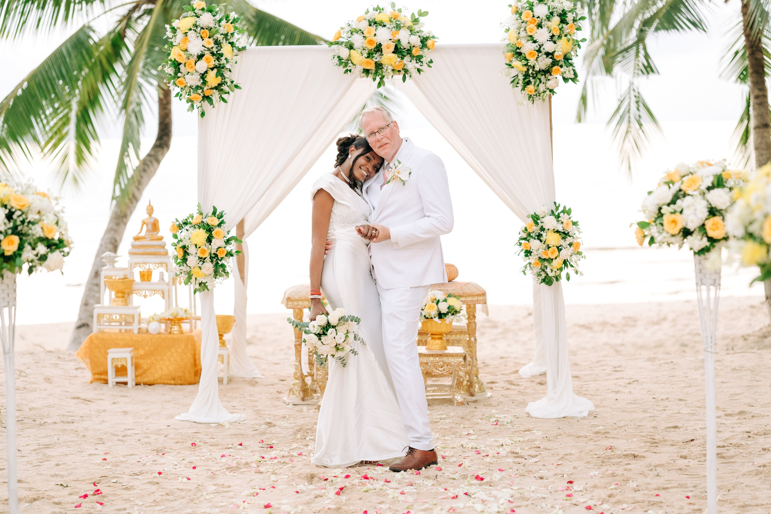Newlywed couple celebrating a Buddhist wedding ceremony on a beautiful beach in Koh Samui, Thailand.