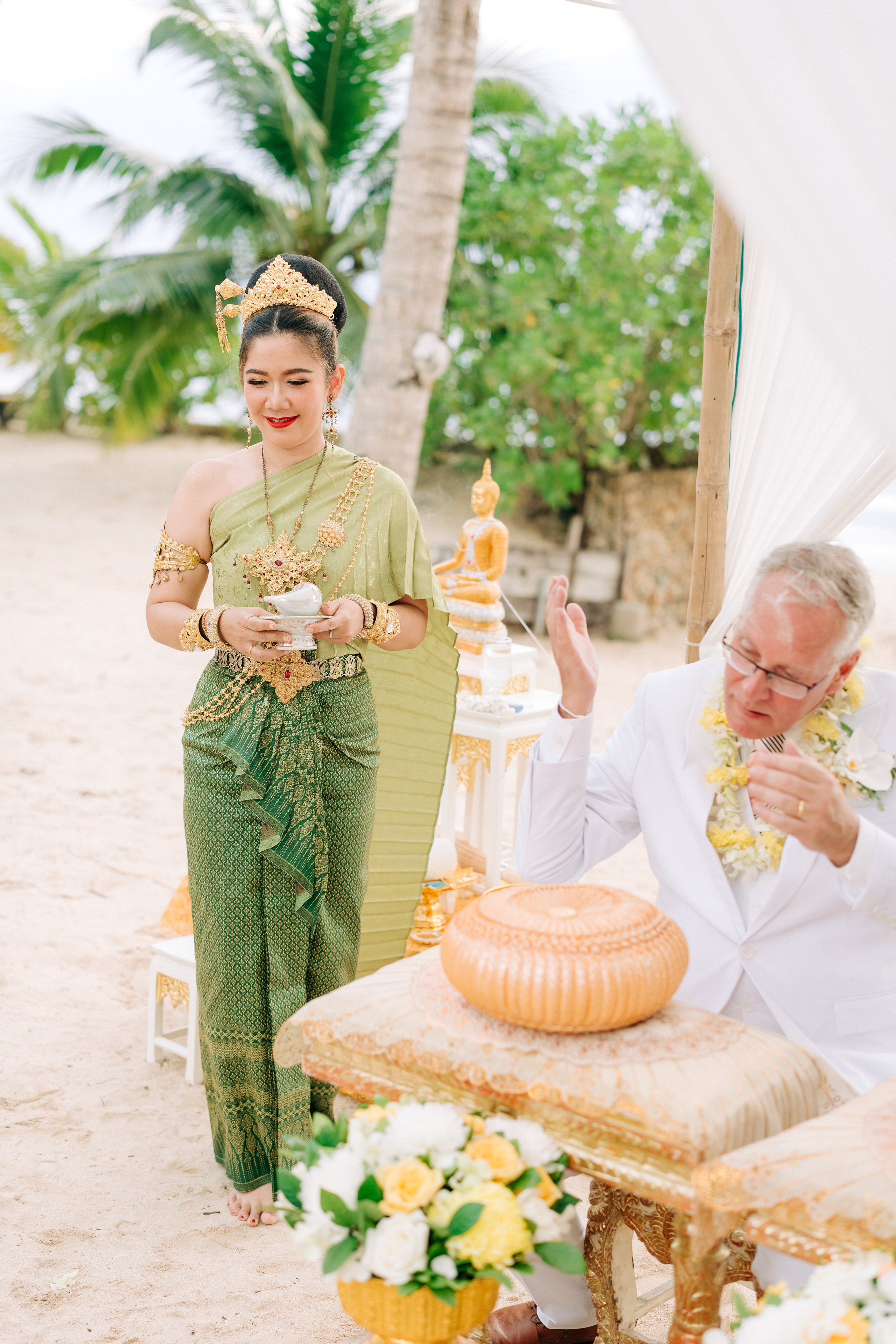 Bride and groom participating in a sacred Buddhist blessing ceremony by the sea in Koh Samui, Thailand.