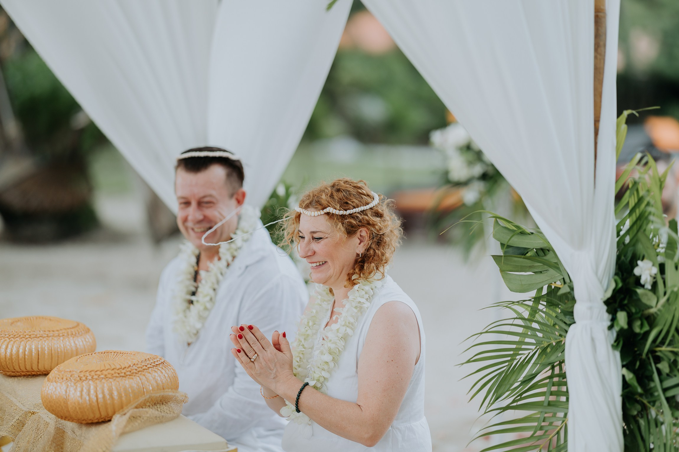 Bride and groom participating in a sacred Buddhist wedding blessing in Thailand