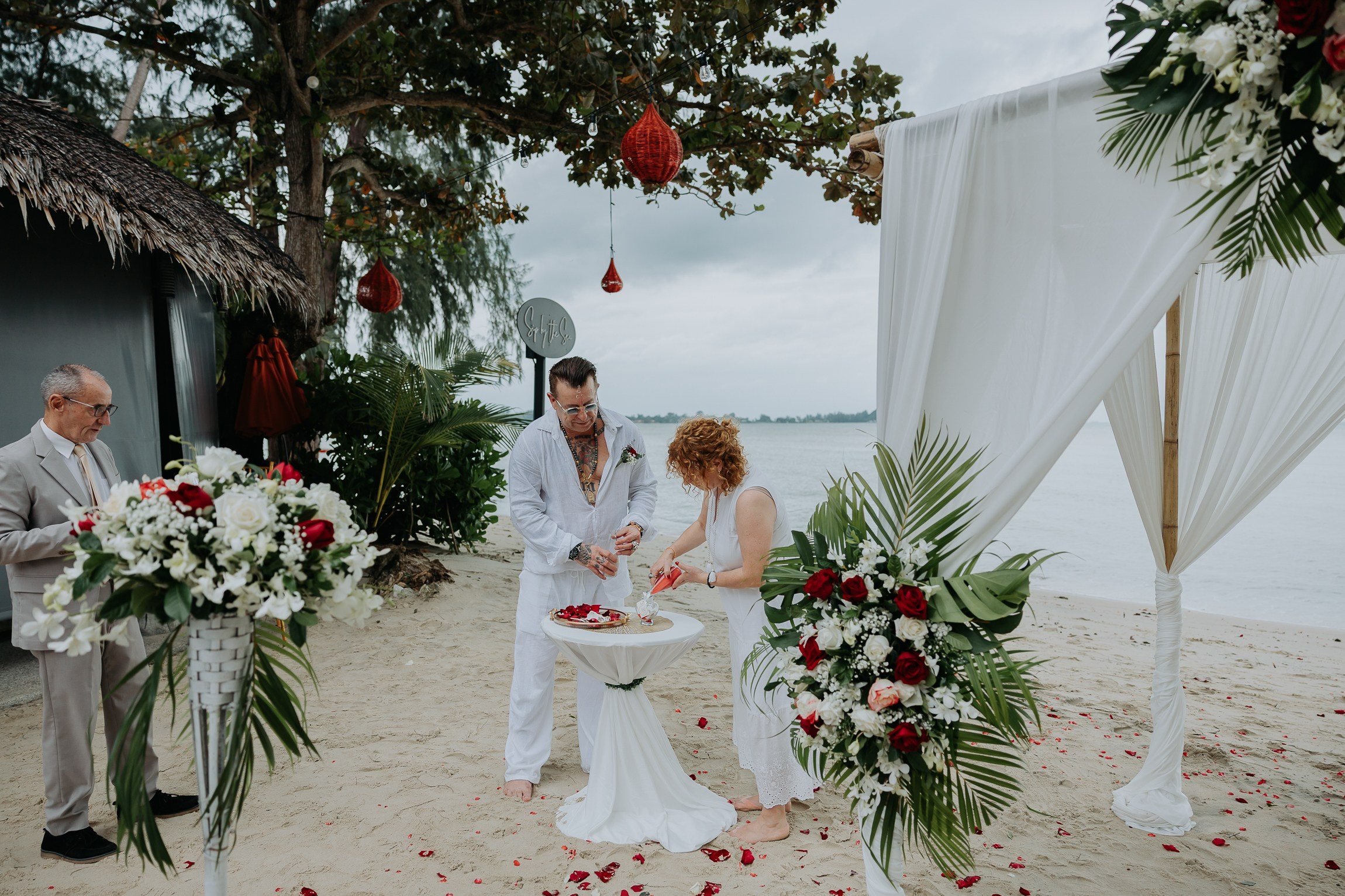 Bride and groom participating in a sacred Buddhist wedding blessing in Thailand