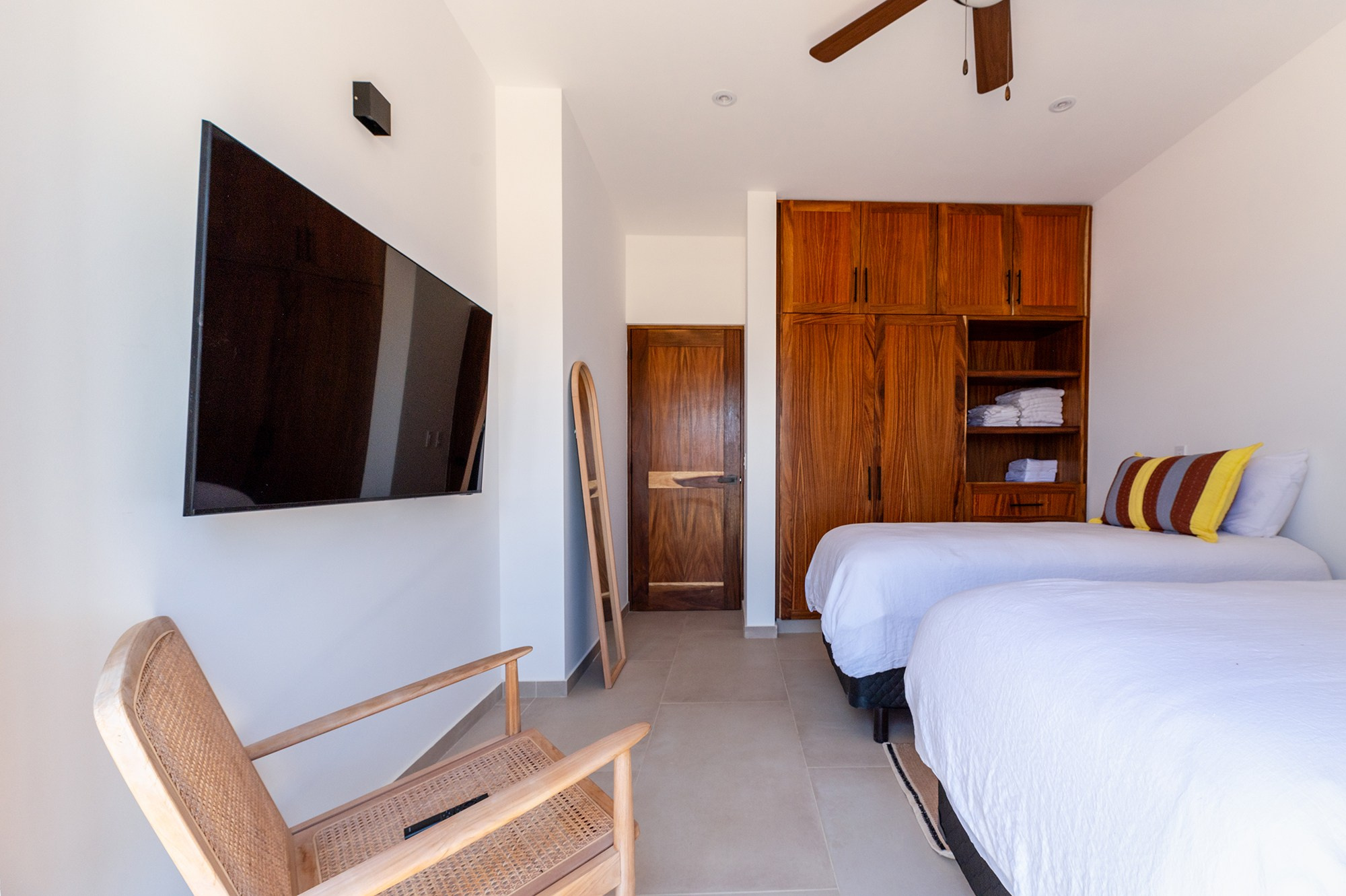 Children’s bedroom in Los Cabos property – double beds, wooden closet and mirror, warm interior real estate photography