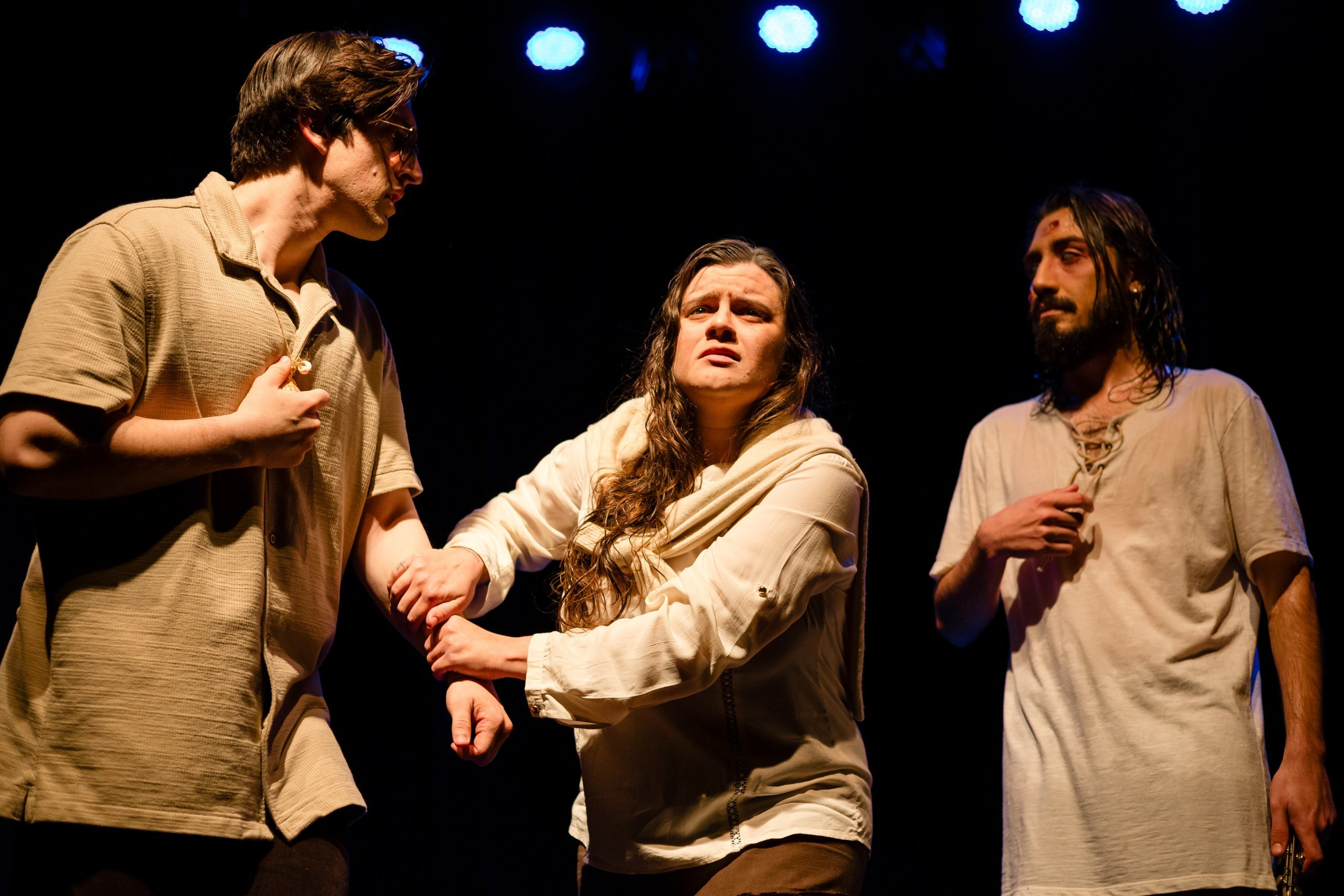 Apresentação teatral com mulher segurando homem e olhando para o horizonte.