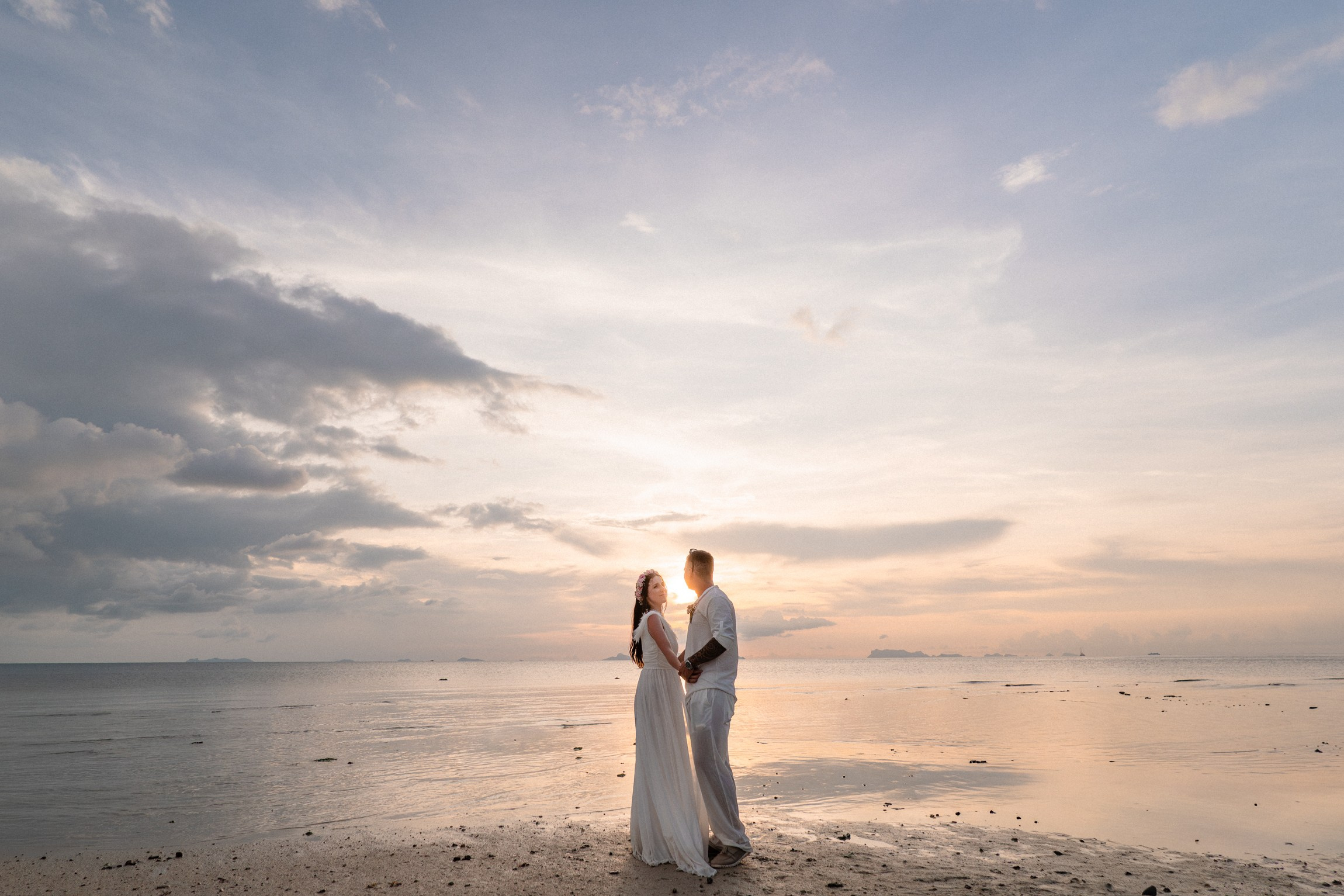 Bride and groom exchanging vows on a private sunset beach