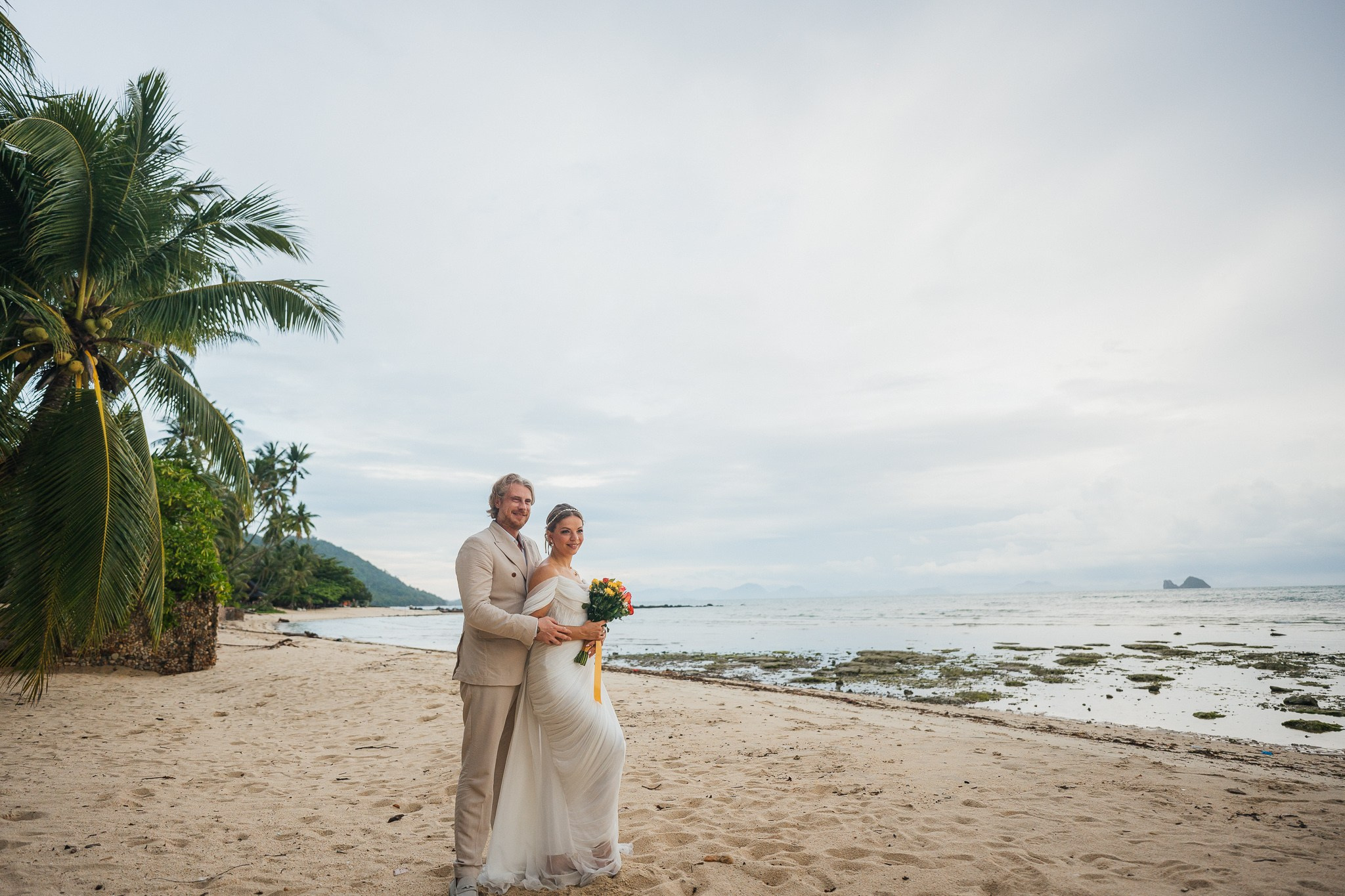 Bride and groom receiving blessings during a Buddhist wedding ceremony on the beach in Koh Samui, Thailand.