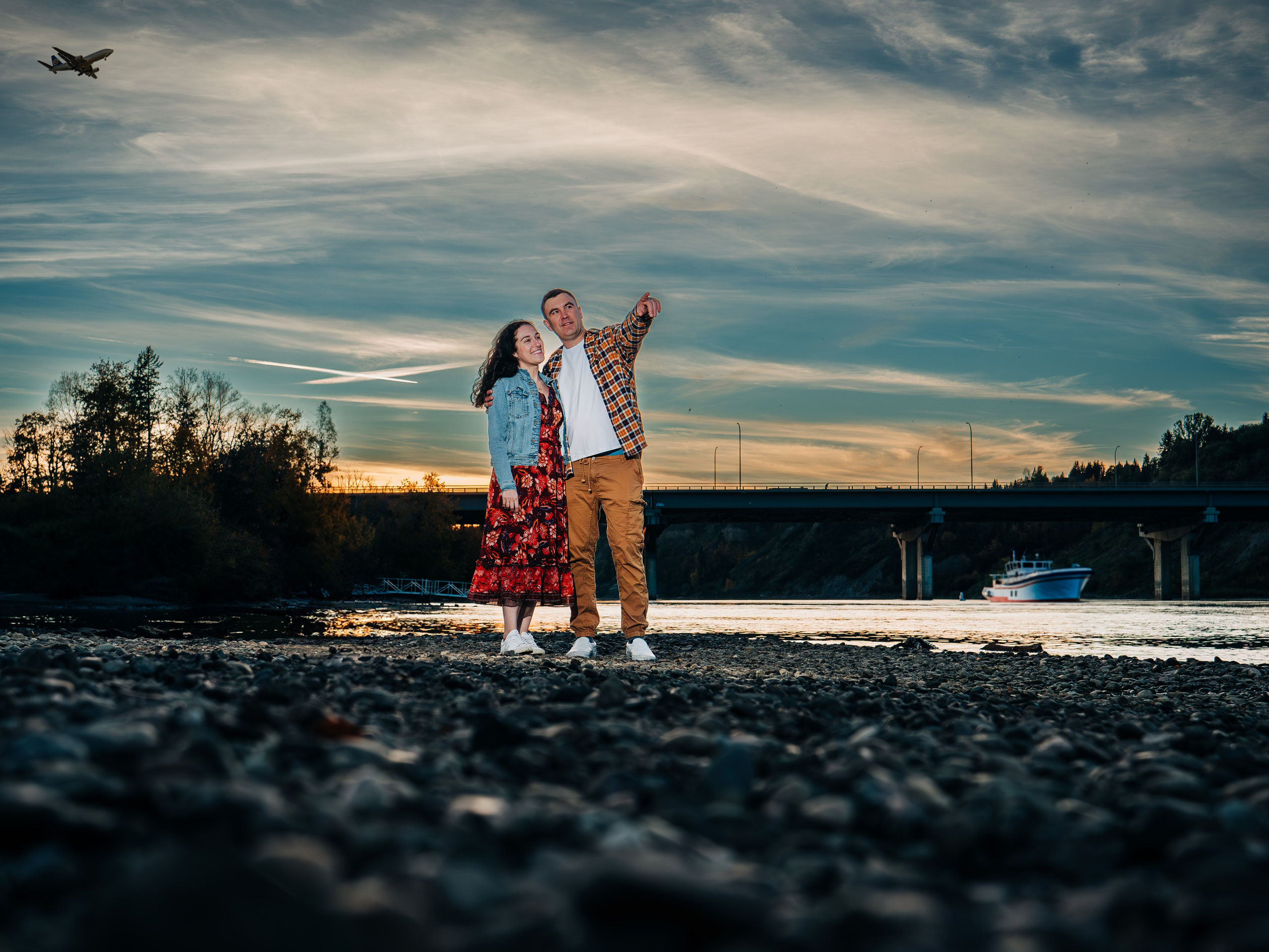 Professional sunset photography in Spruce Grove by Dimitri Studio. Couple standing on a rocky riverbank at dusk looking over the water. View portfolio at dimitristudio.com