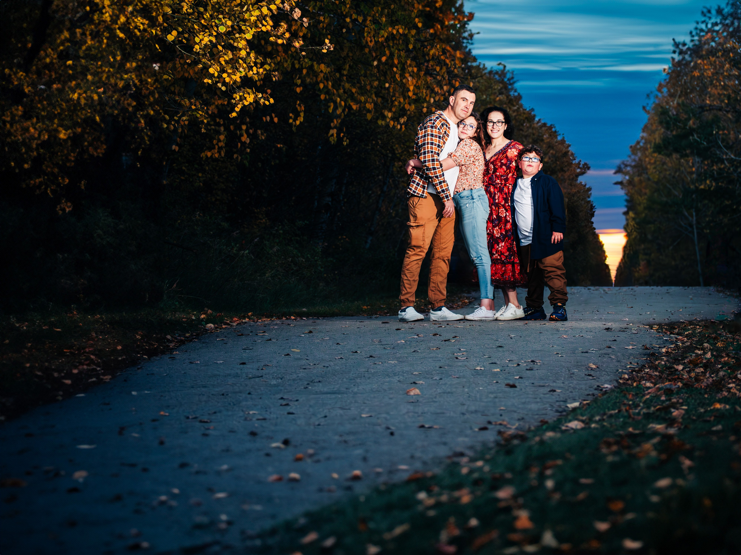 Outdoor family photography by Dimitri Studio. Family posing on a path surrounded by autumn trees at twilight in Spruce Grove. Visit dimitristudio.com