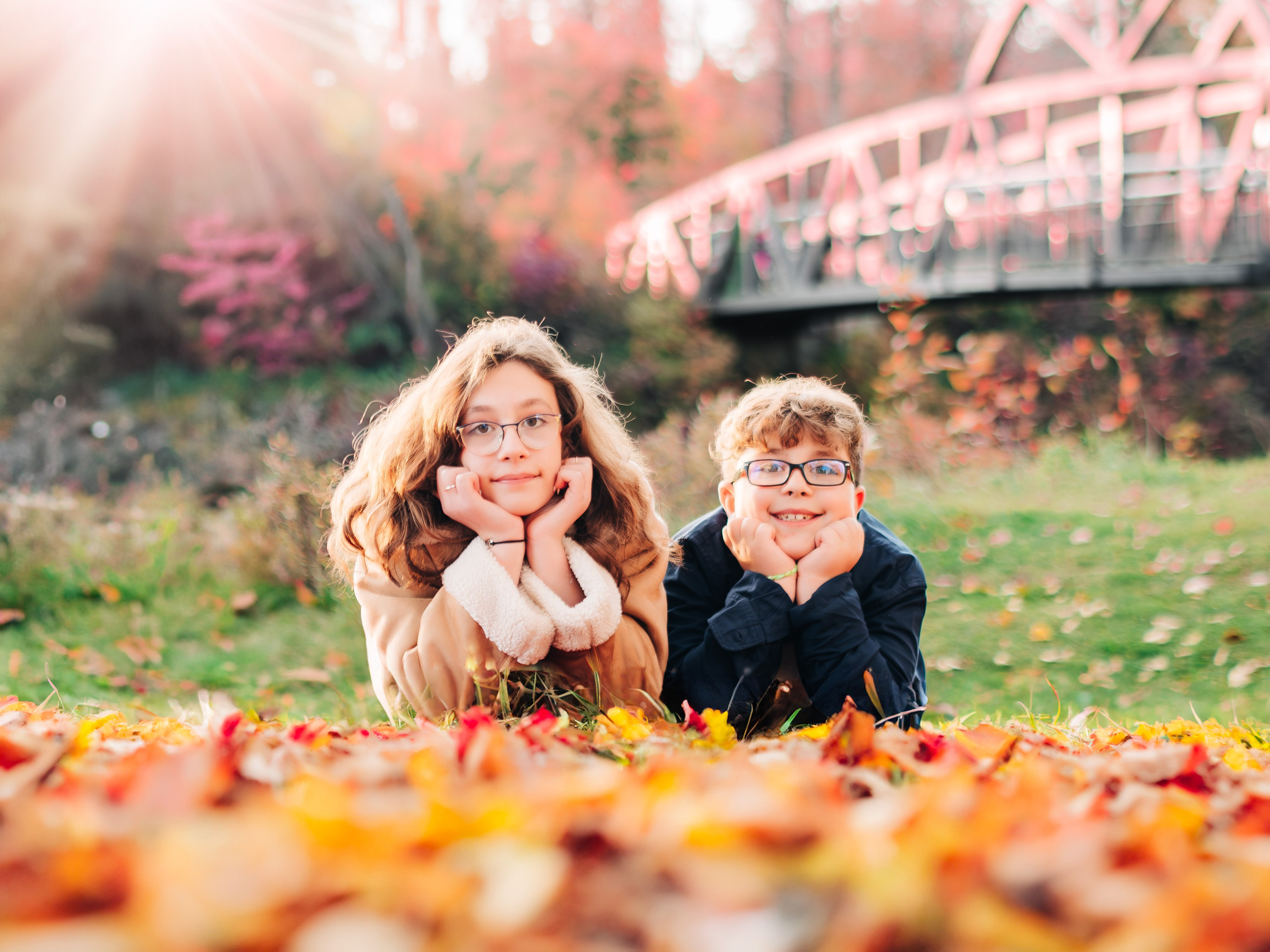 Professional children and portrait photography by Dimitri Studio. Two kids laying in vibrant autumn leaves in a Spruce Grove park. View portfolio at dimitristudio.com