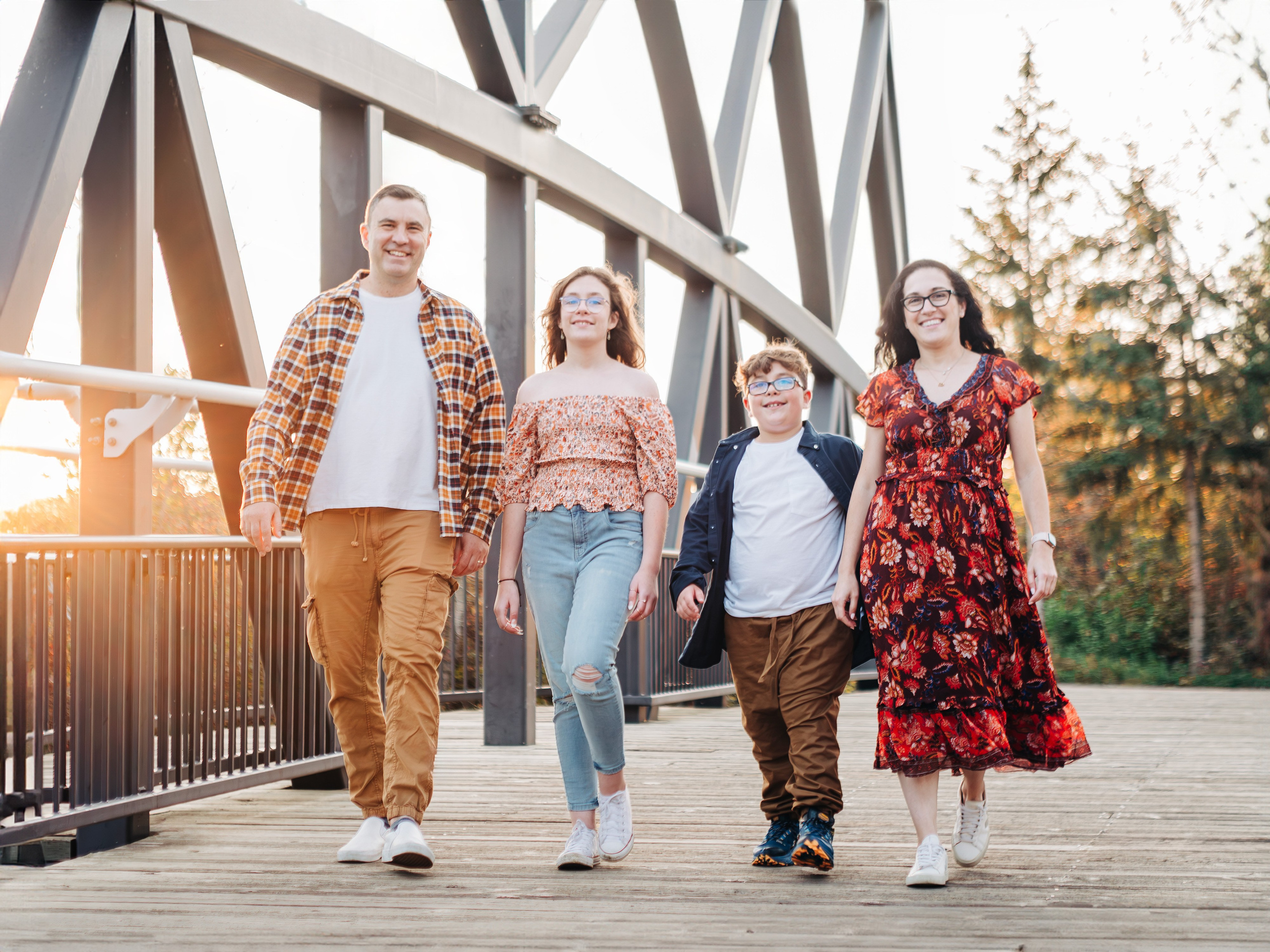 Outdoor family event photography in Spruce Grove by Dimitri Studio. Family walking together across a modern footbridge at sunset. Book your session at dimitristudio.com