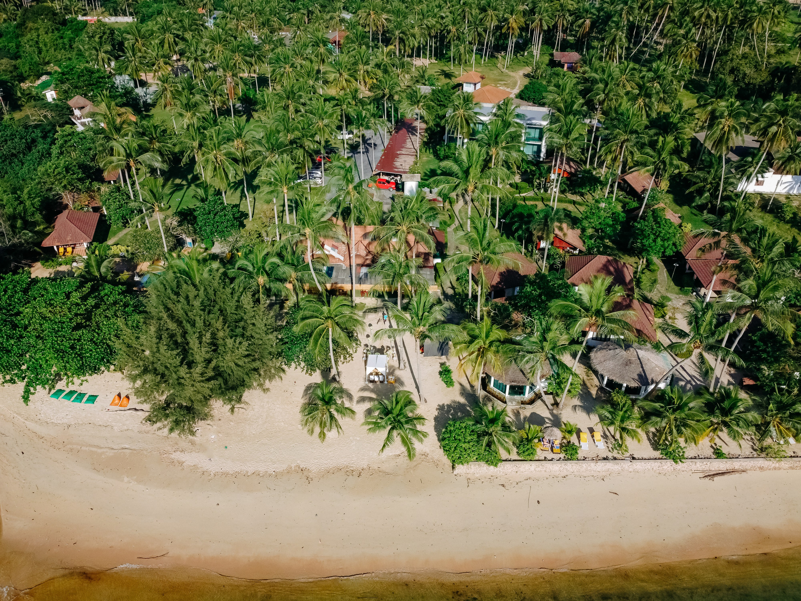 Bride and groom participating in a sacred Buddhist blessing ceremony by the sea in Koh Samui, Thailand.