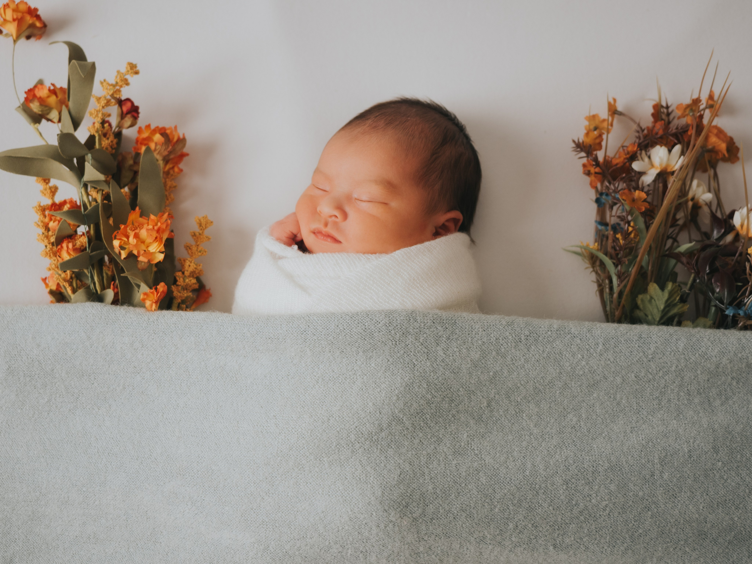 Bébé nouveau-né endormi sous une couverture.