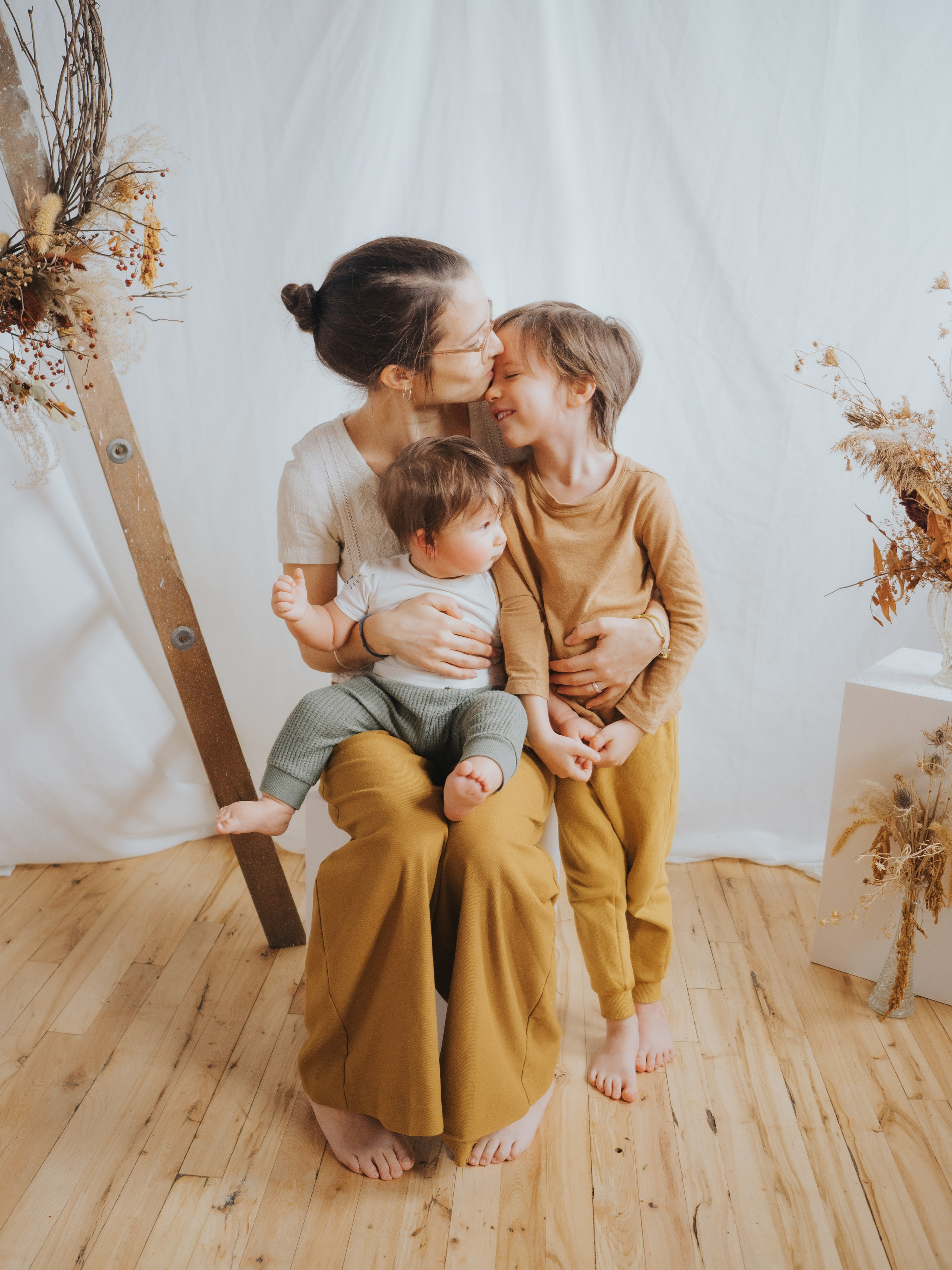 La mère donne un baiser sur le front au frère aîné.