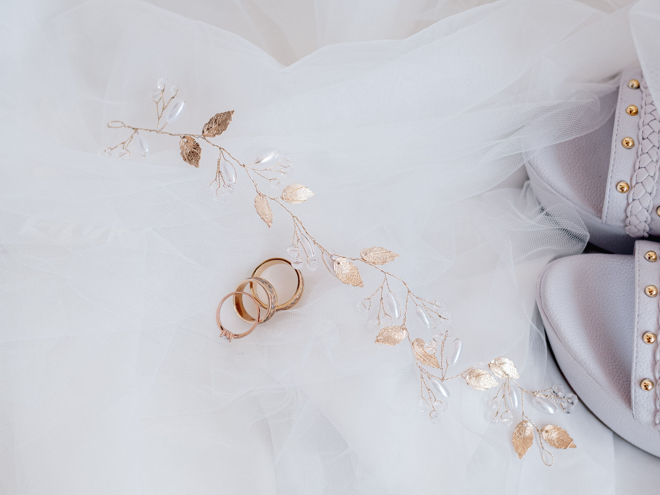 Detalles de novia con anillos de boda y pulsera en fondo blanco, preparativos de boda