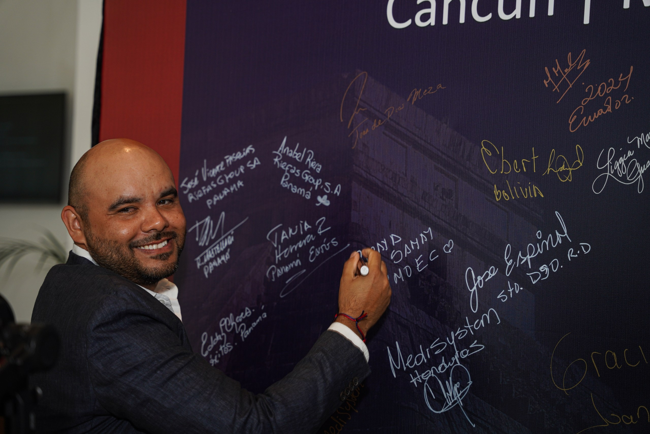 Guest writing message on branded event wall at conference.
