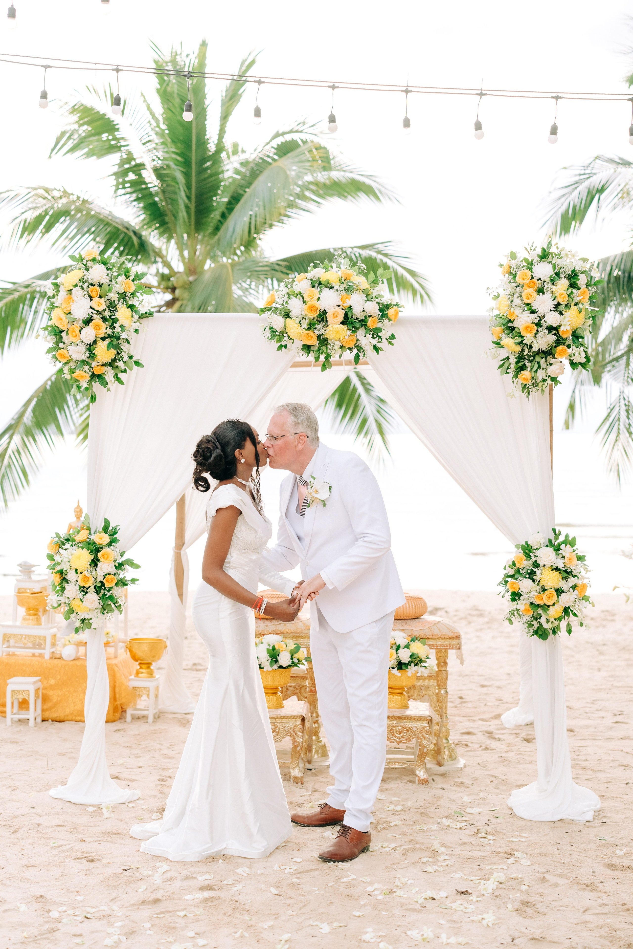 Newlywed couple celebrating a Buddhist wedding ceremony on a beautiful beach in Koh Samui, Thailand.