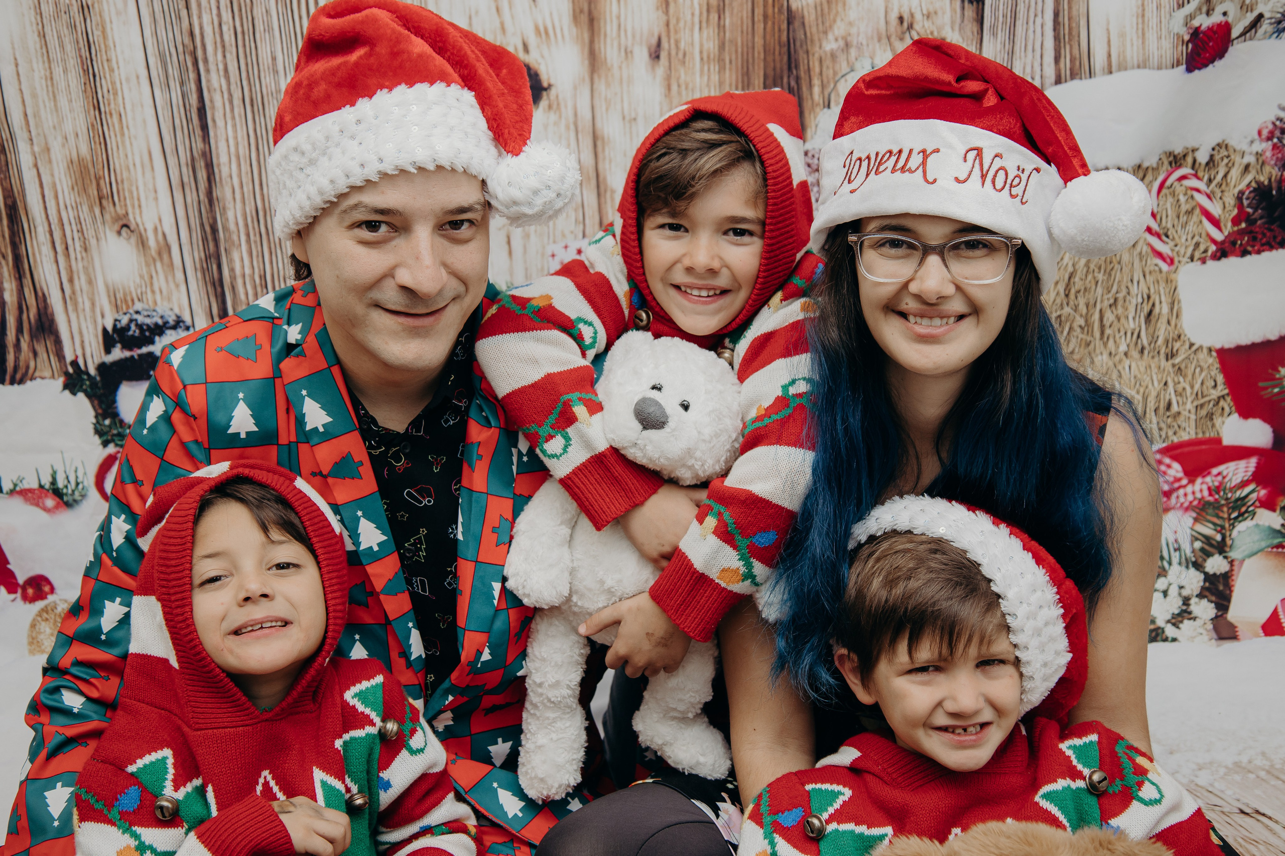 Family of five wearing festive Christmas outfits posing together for a holiday family photoshoot in Calgary.