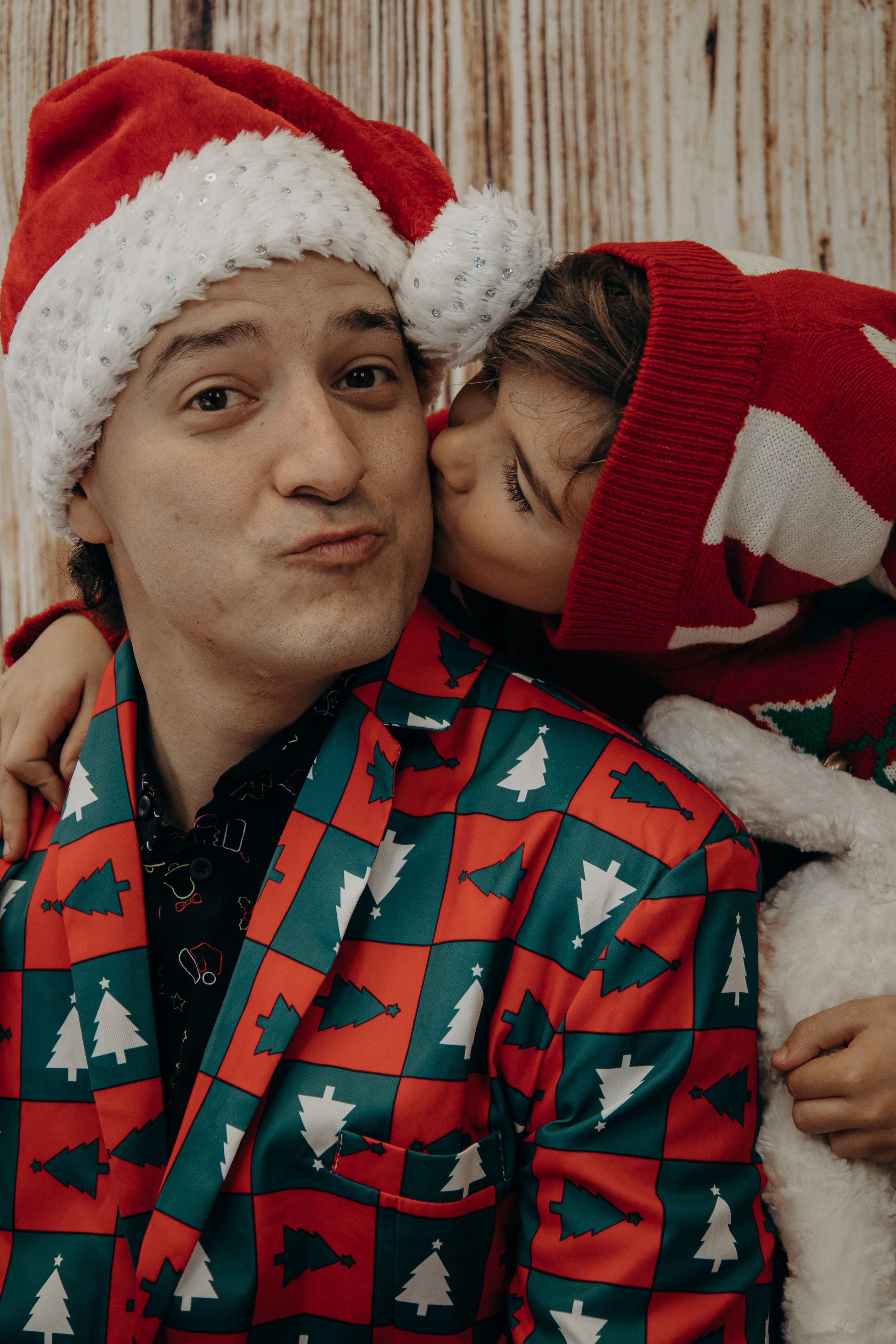Young child kissing his father on the cheek in a warm, candid Christmas family portrait.