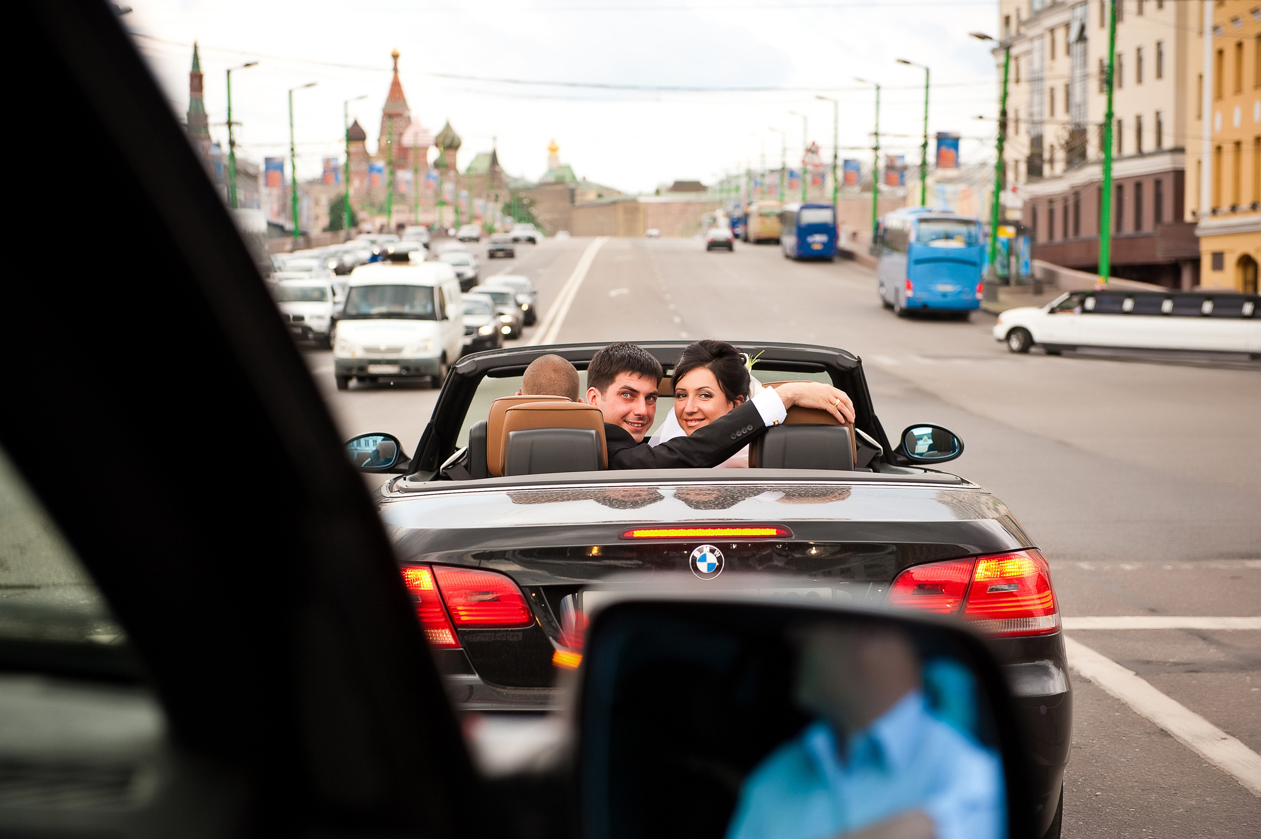 Свадебная фотосессия в Москве. Жених и невеста едут в кабриолете по Красной площади