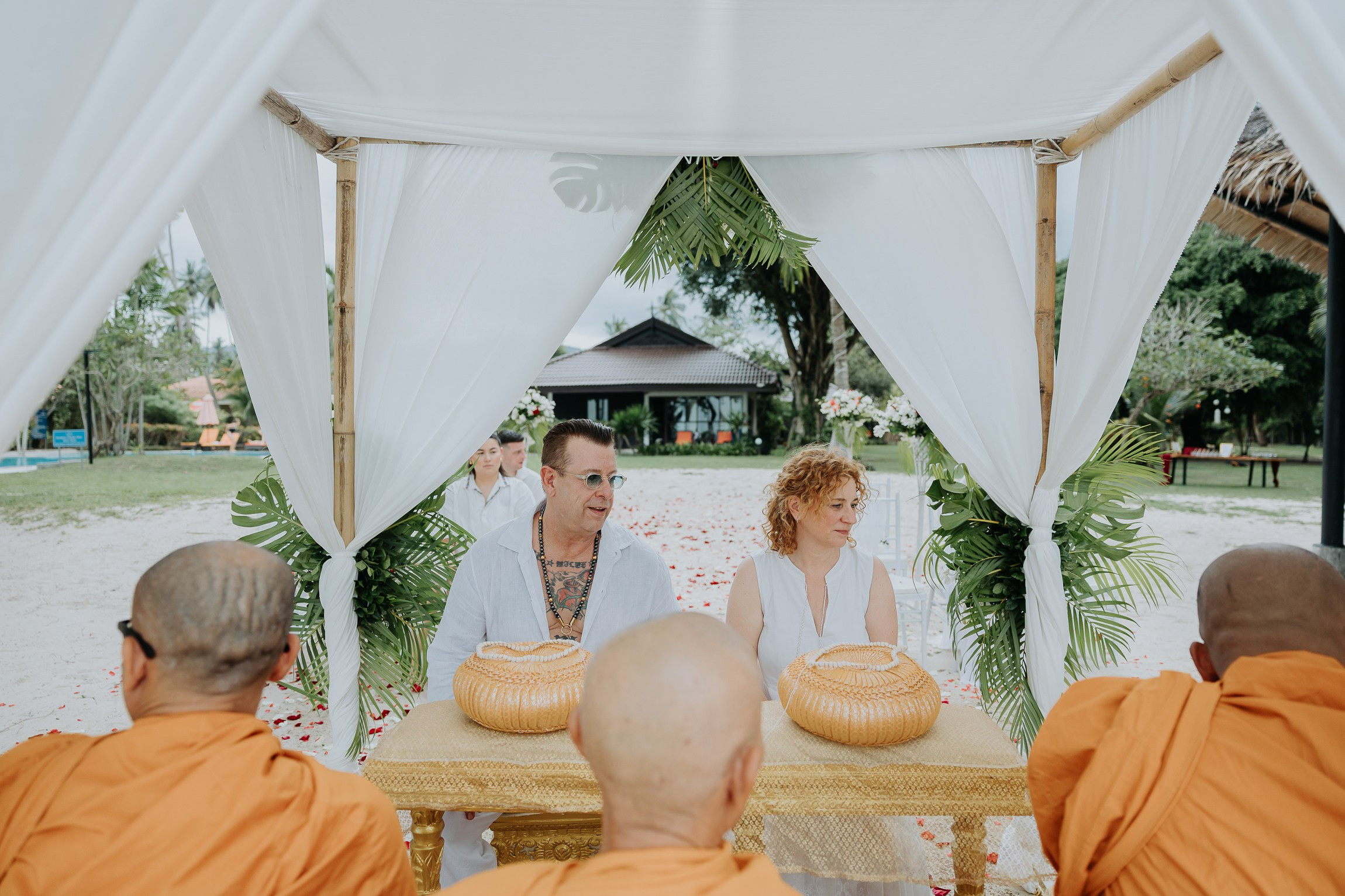 Bride and groom participating in a sacred Buddhist wedding blessing in Thailand