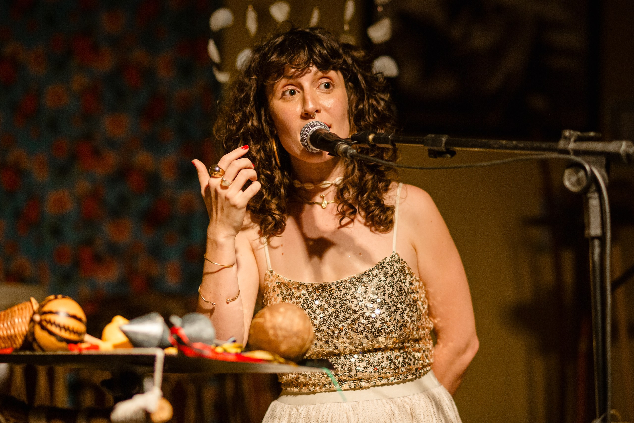 Fotógrafo de show em Balneário Camboriú; a cantora Joana Gaia interagindo com o público ao microfone ao lado de instrumentos de percussão durante show no bairro da Barra para a divulgação do álbum "Água Brasileira".