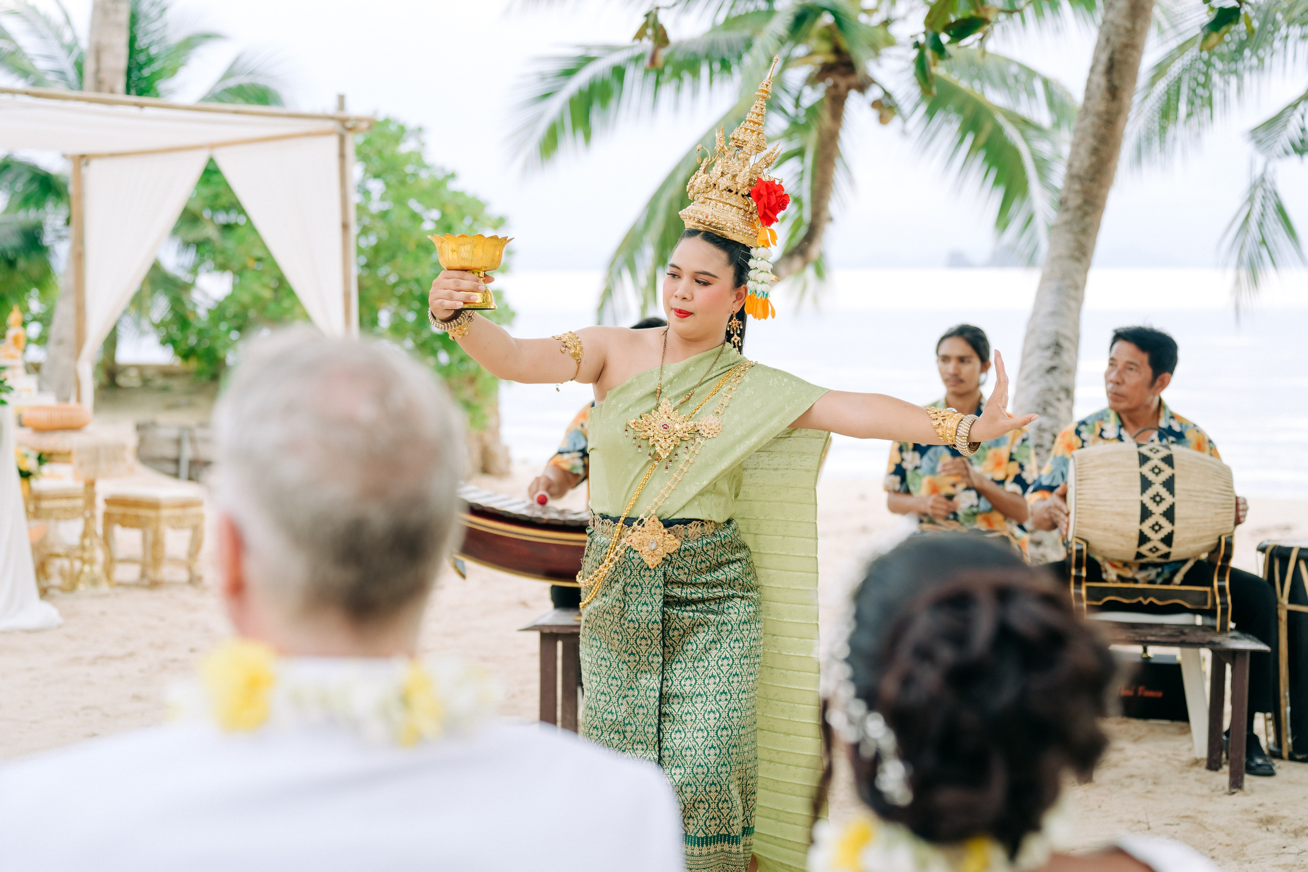 Couple taking part in a traditional Buddhist wedding ceremony on a tropical beach in Koh Samui, Thailand, with monks, flowers, and ocean views.
