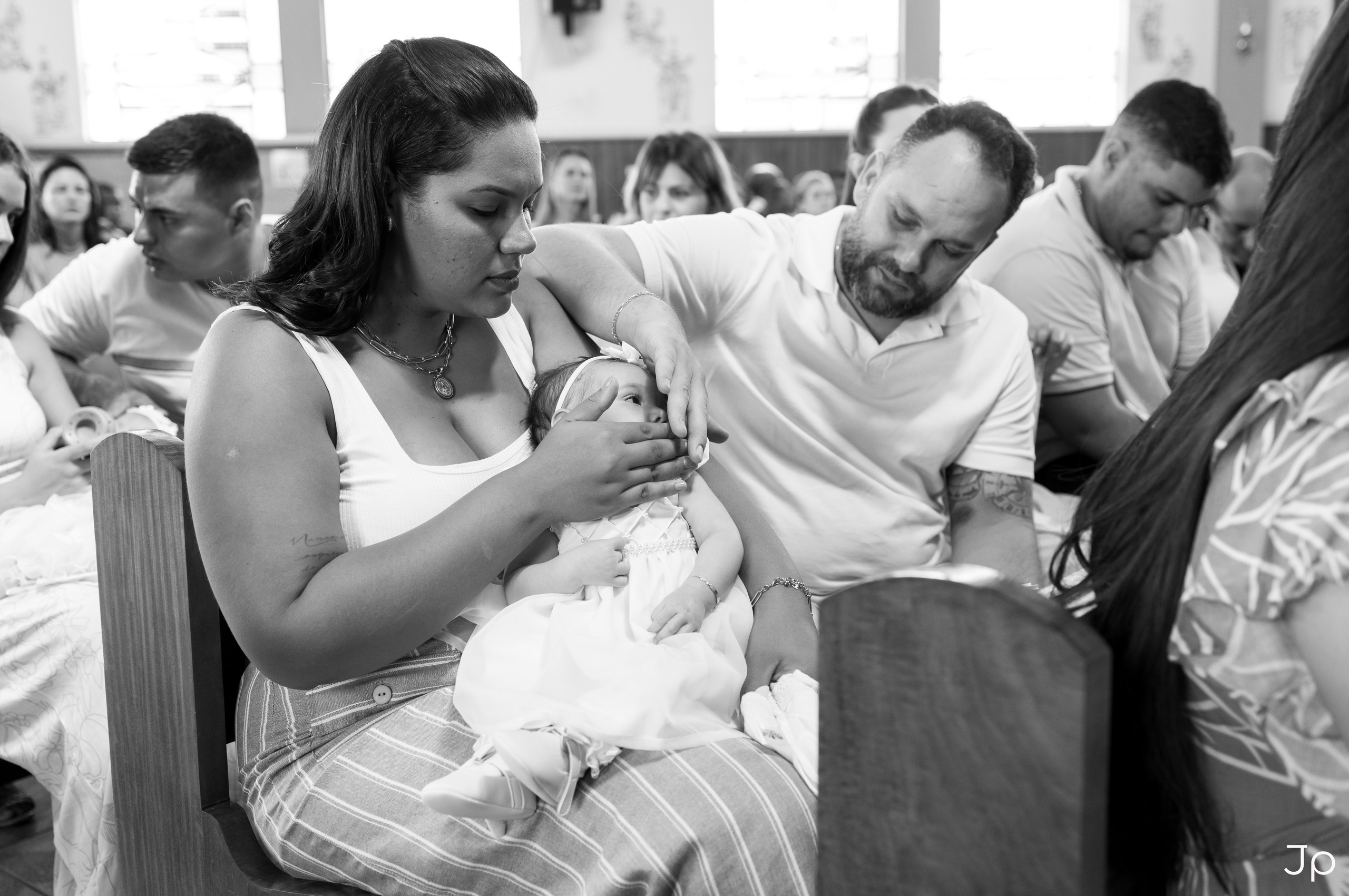 Mãe e pai trocando fralda do bebê no banco da igreja.
