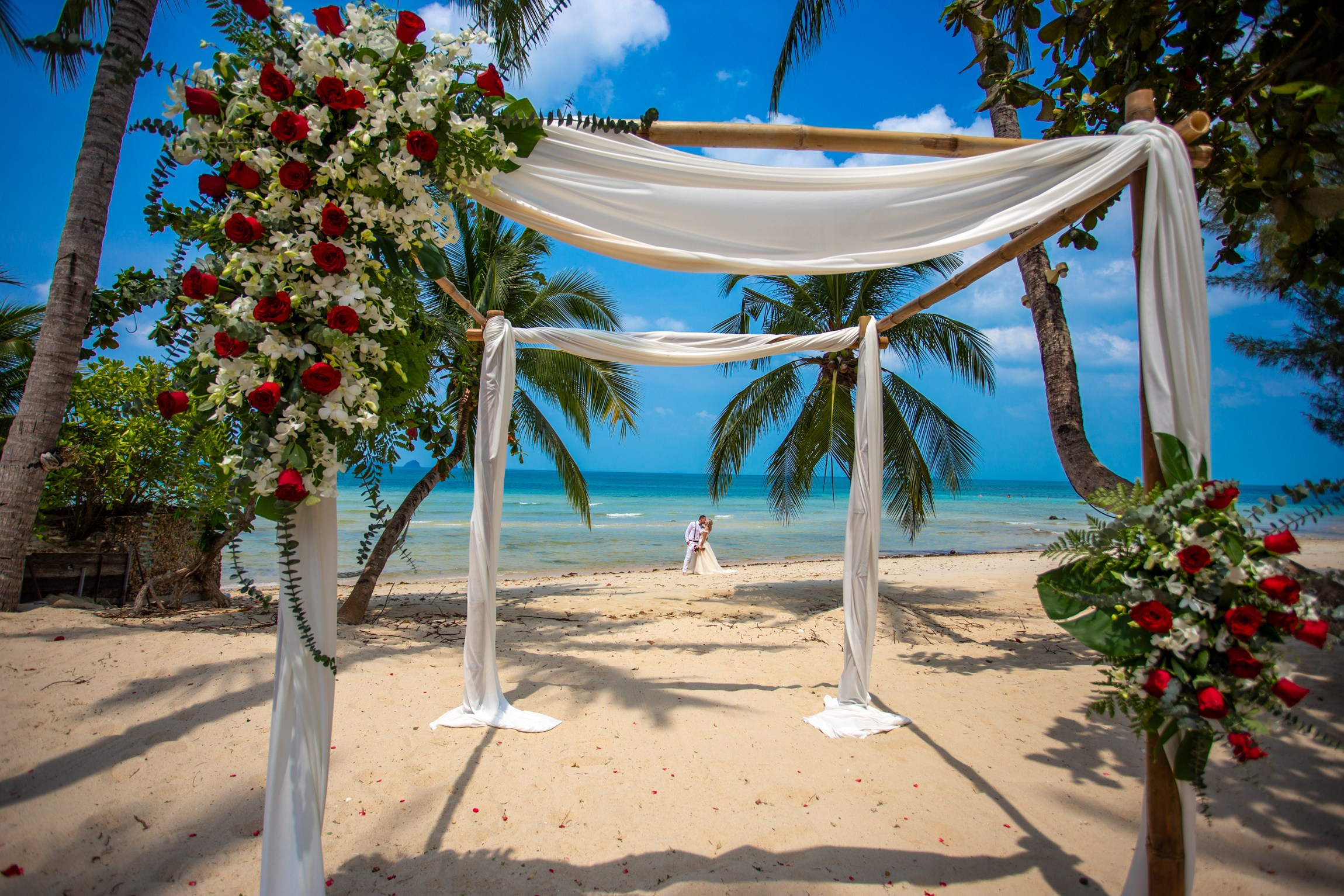 Elegant beach wedding setup on Koh Samui, Thailand with bride, groom, flowers and stunning sea backdrop