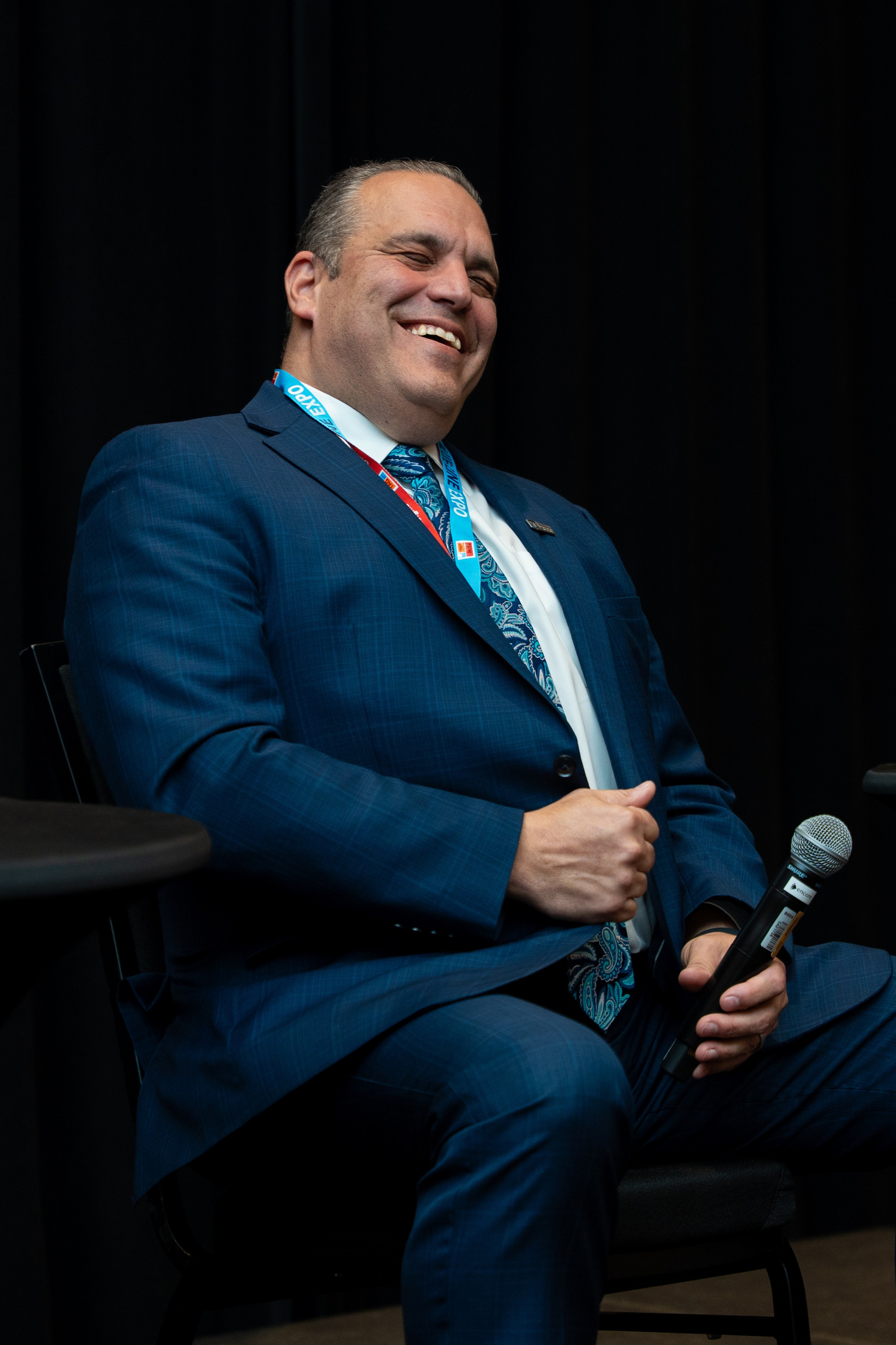 Formal portrait of speaker in navy suit, Blueline Expo 2026