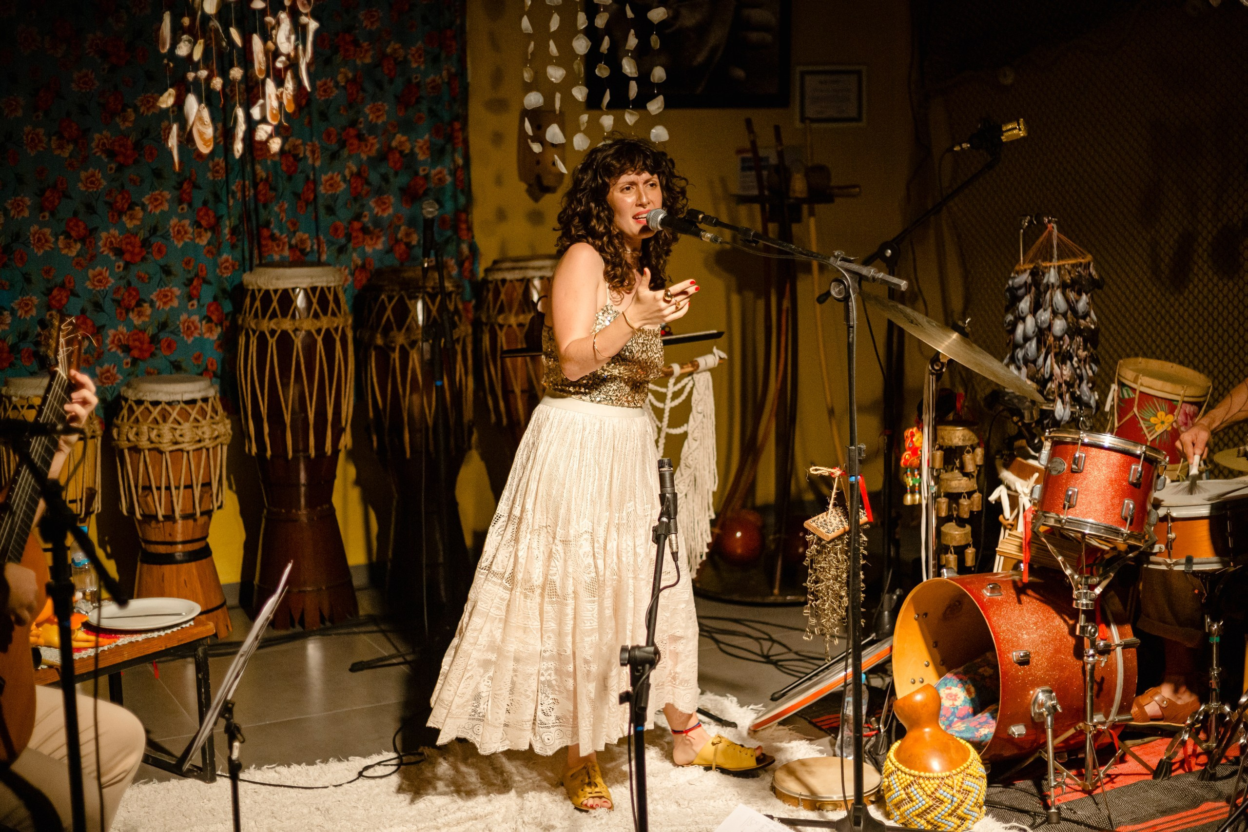 Fotógrafo de show em Balneário Camboriú; a cantora Joana Gaia em plano aberto no palco durante apresentação no bairro da Barra para a divulgação do álbum "Água Brasileira".