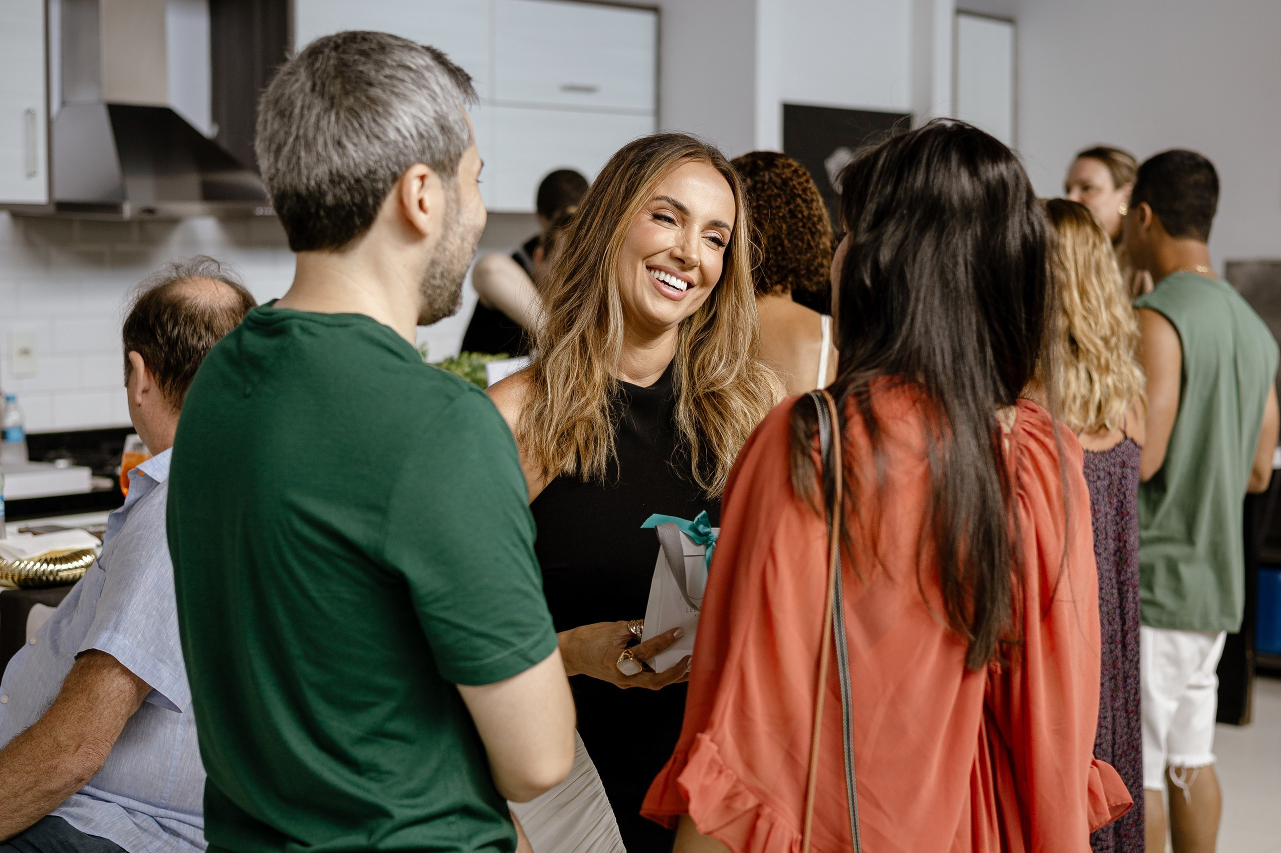 Fotografia de cobertura de festa e evento em Itajaí retratando a aniversariante sorridente conversando e interagindo com os convidados durante a celebração.