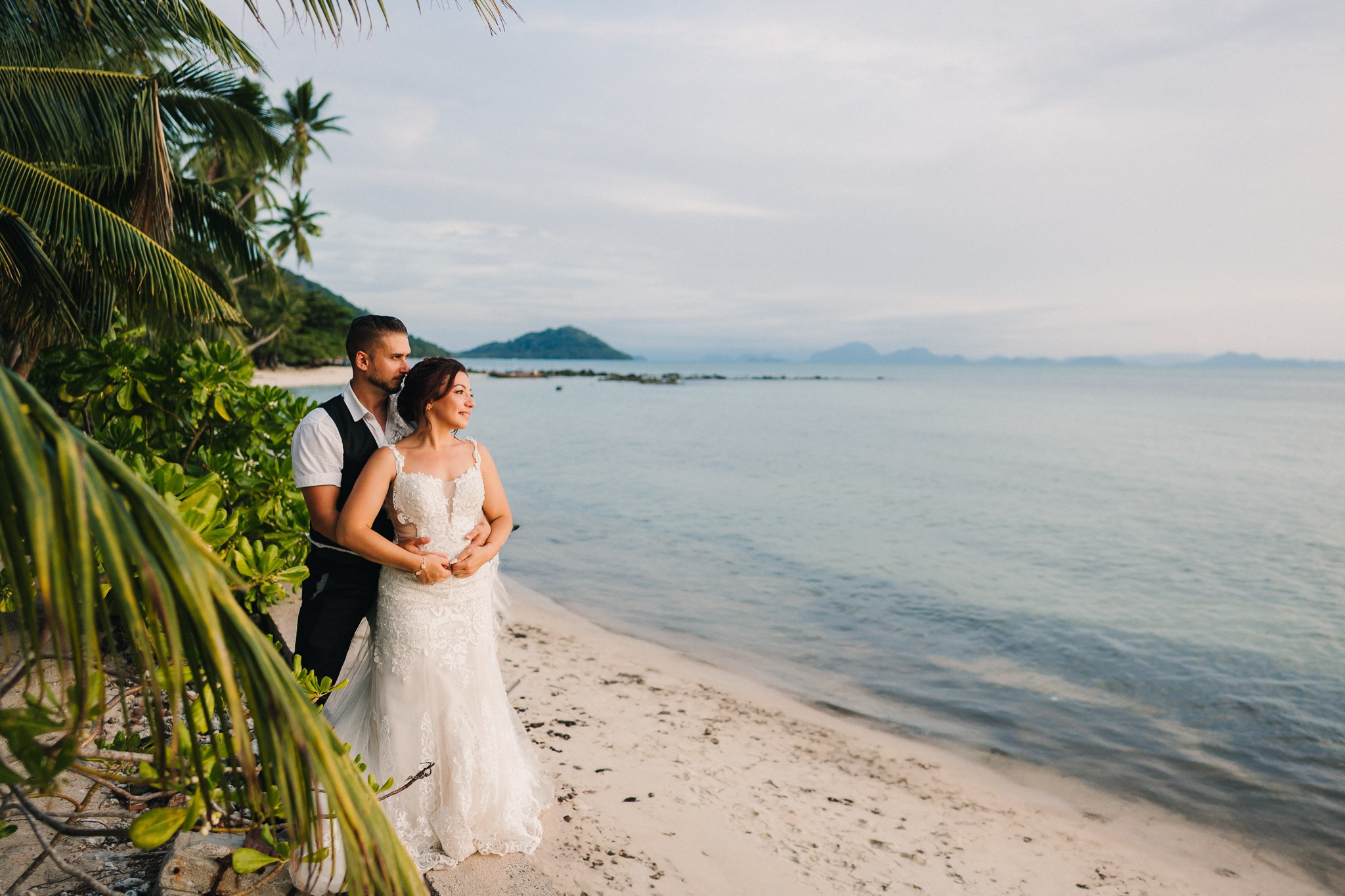 Bride and groom celebrating a beach wedding with their children in Koh Samui, Thailand, surrounded by tropical scenery and ocean views