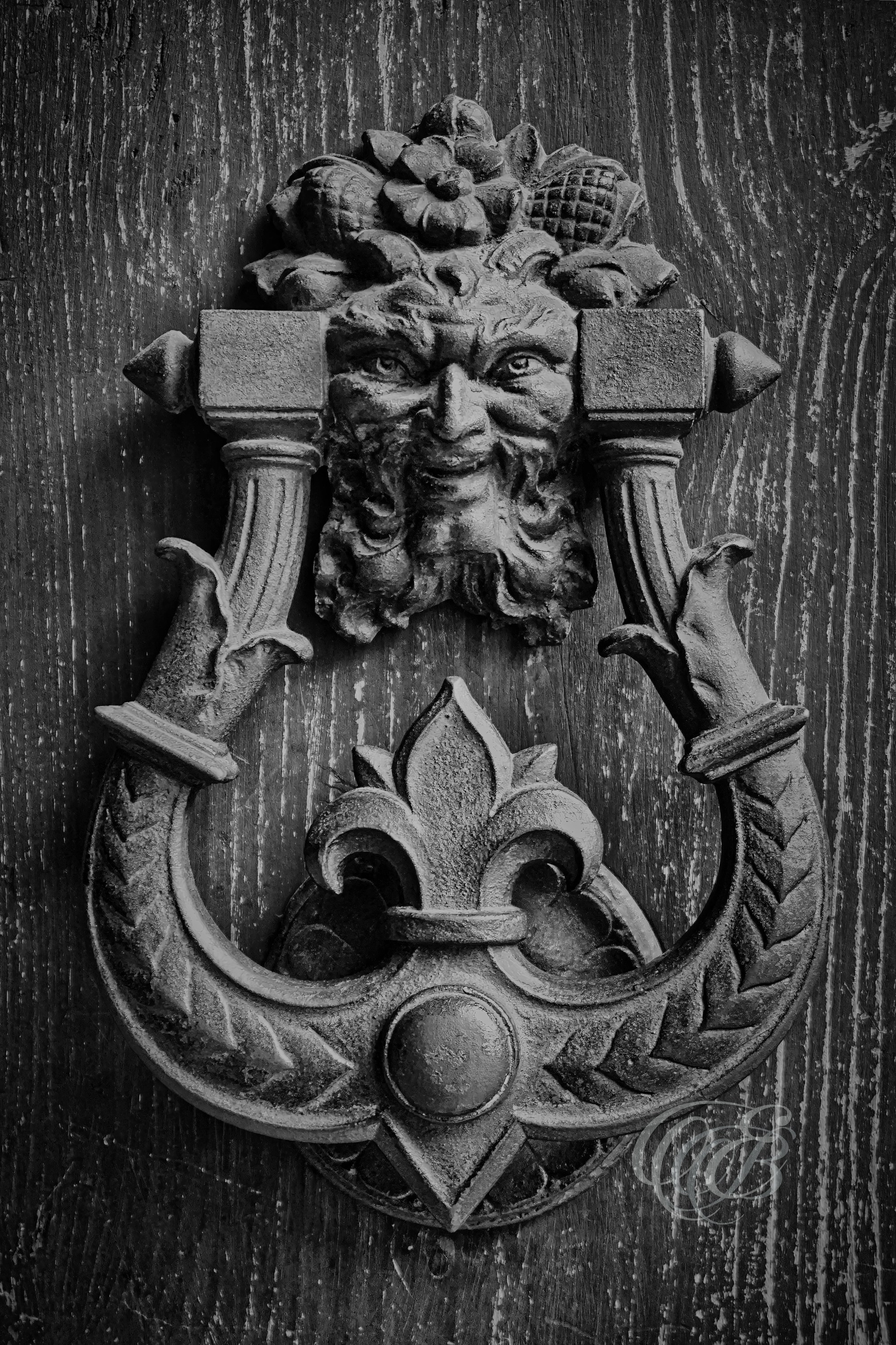 ITALY – FLORENCE — Antique Door Knocker Detail Black and White — Close-up view of weathered metal door knocker on historic Florentine building, showing ornate craftsmanship, aged surface texture, and architectural detail, Florence, Italy — Eduardo Bartoli Photography.