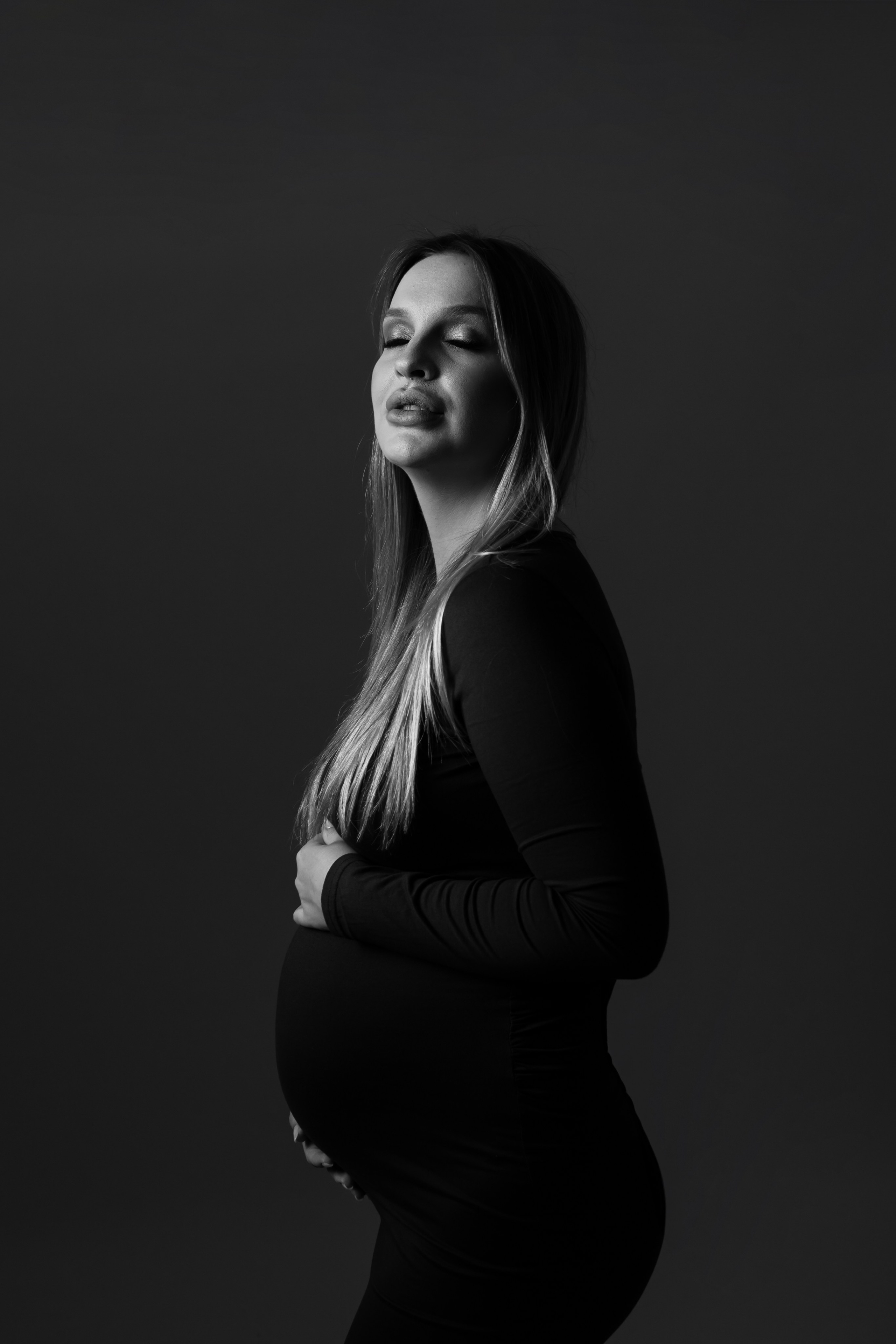 Retrato artístico em preto e branco de gestante com vestido justo, expressando conexão emocional e serenidade