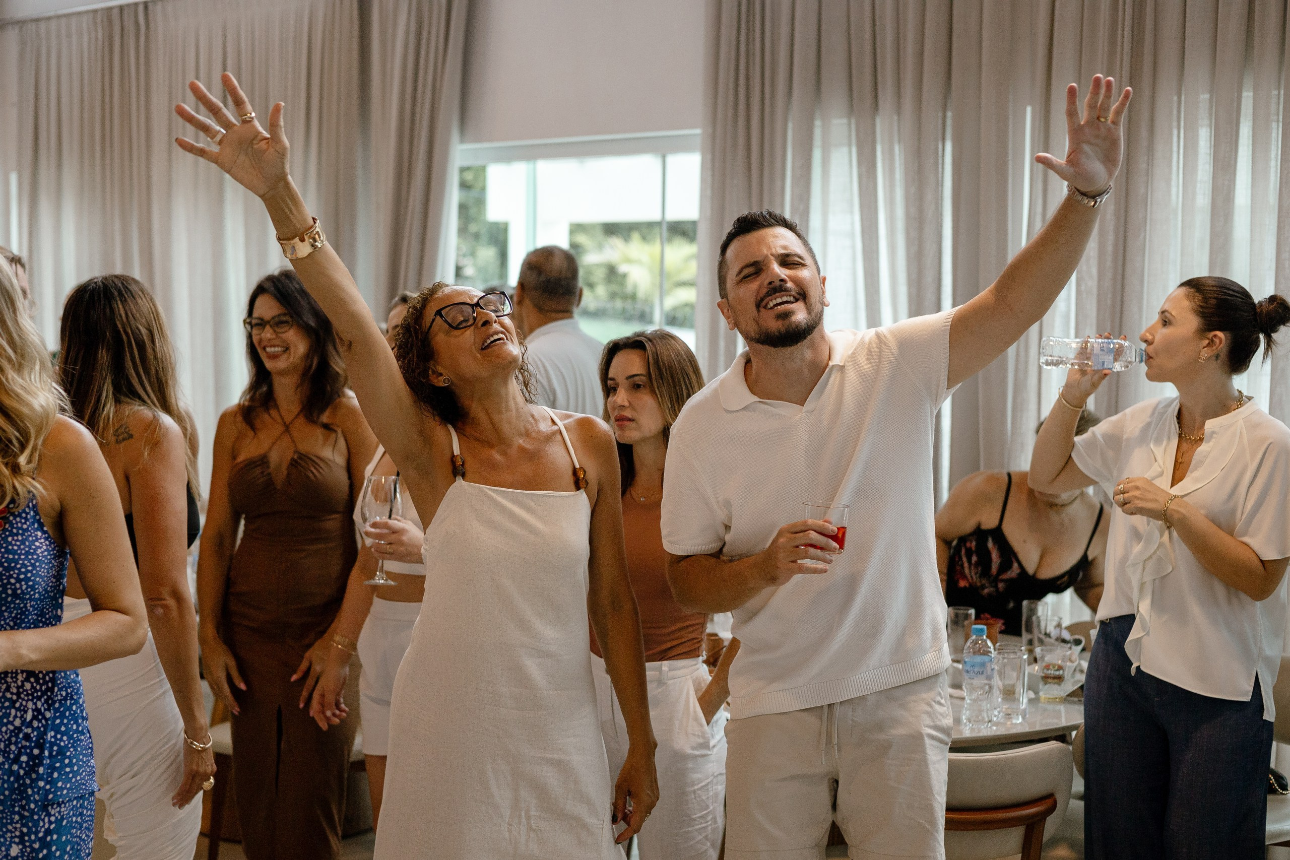 Fotografia de cobertura de festa e de evento em Itajaí capturando convidados a celebrar com entusiasmo e os braços levantados durante a comemoração.