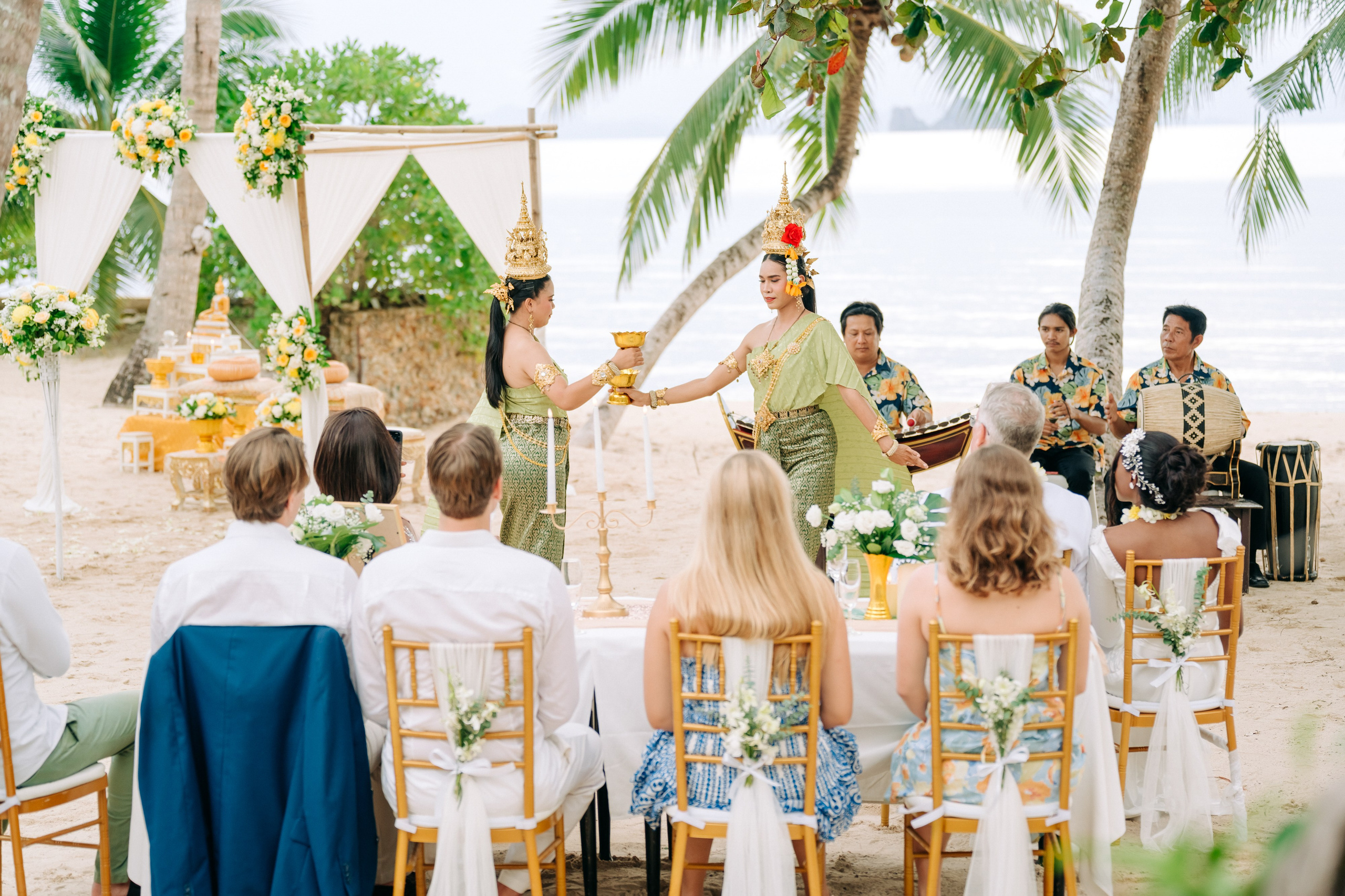 Newlywed couple celebrating a Buddhist wedding ceremony on a beautiful beach in Koh Samui, Thailand.