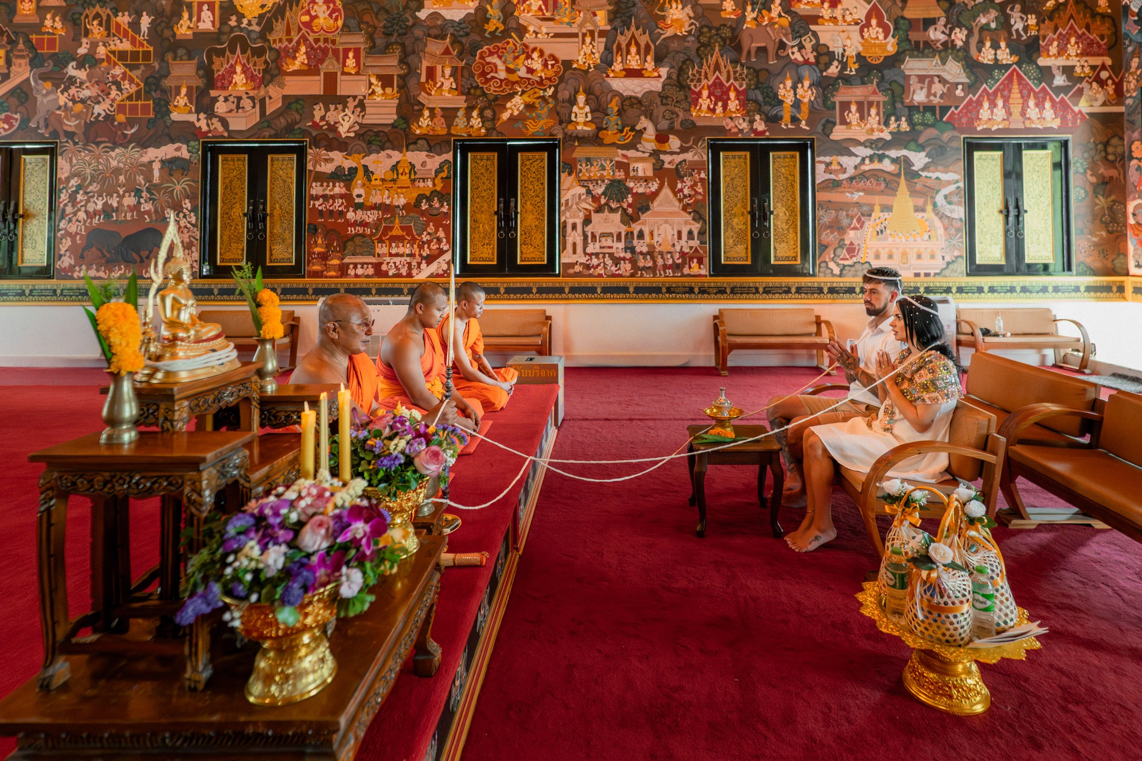 Bride and groom participating in a sacred Buddhist wedding blessing in Thailand