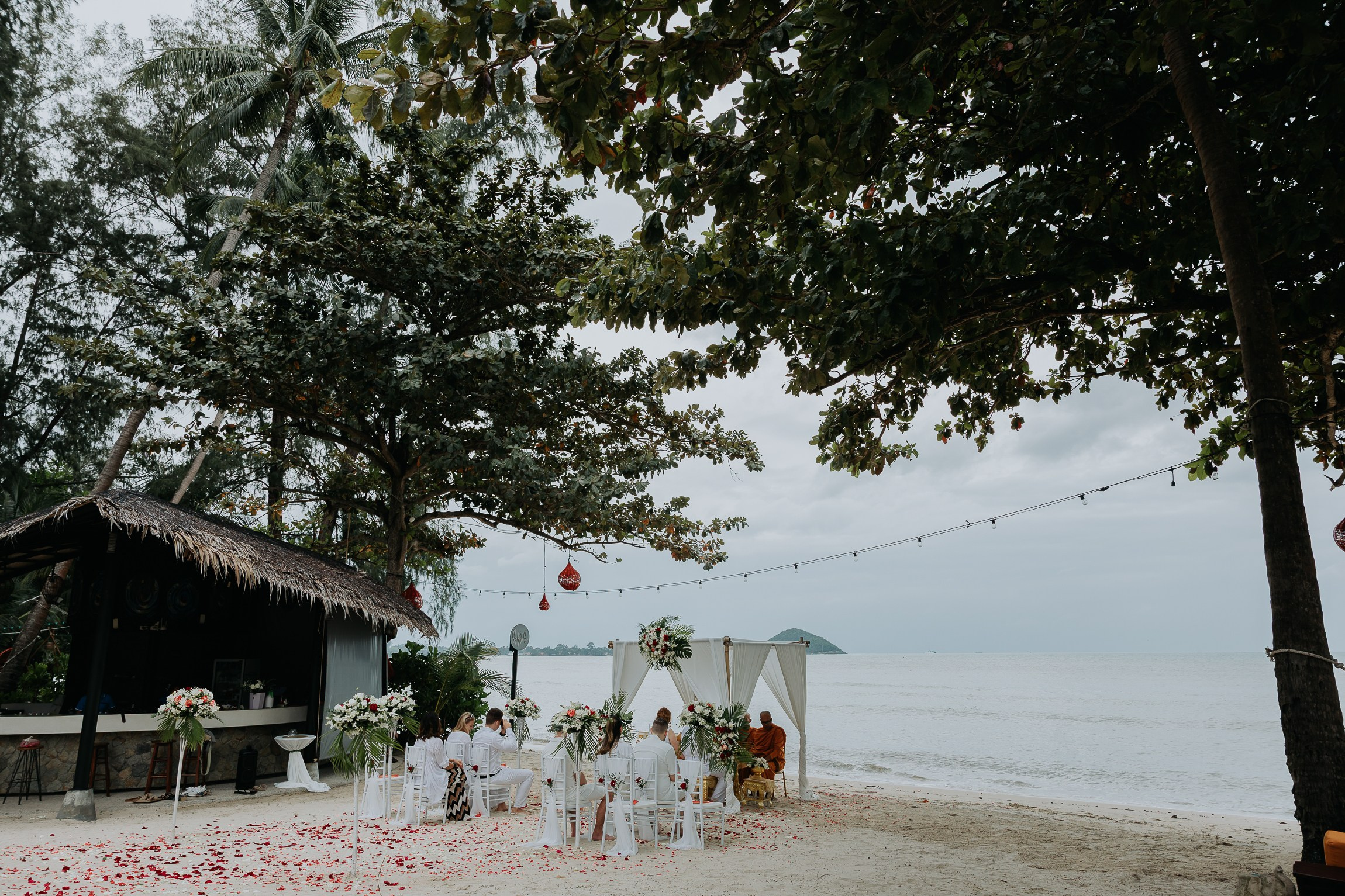 Bride and groom participating in a sacred Buddhist wedding blessing in Thailand